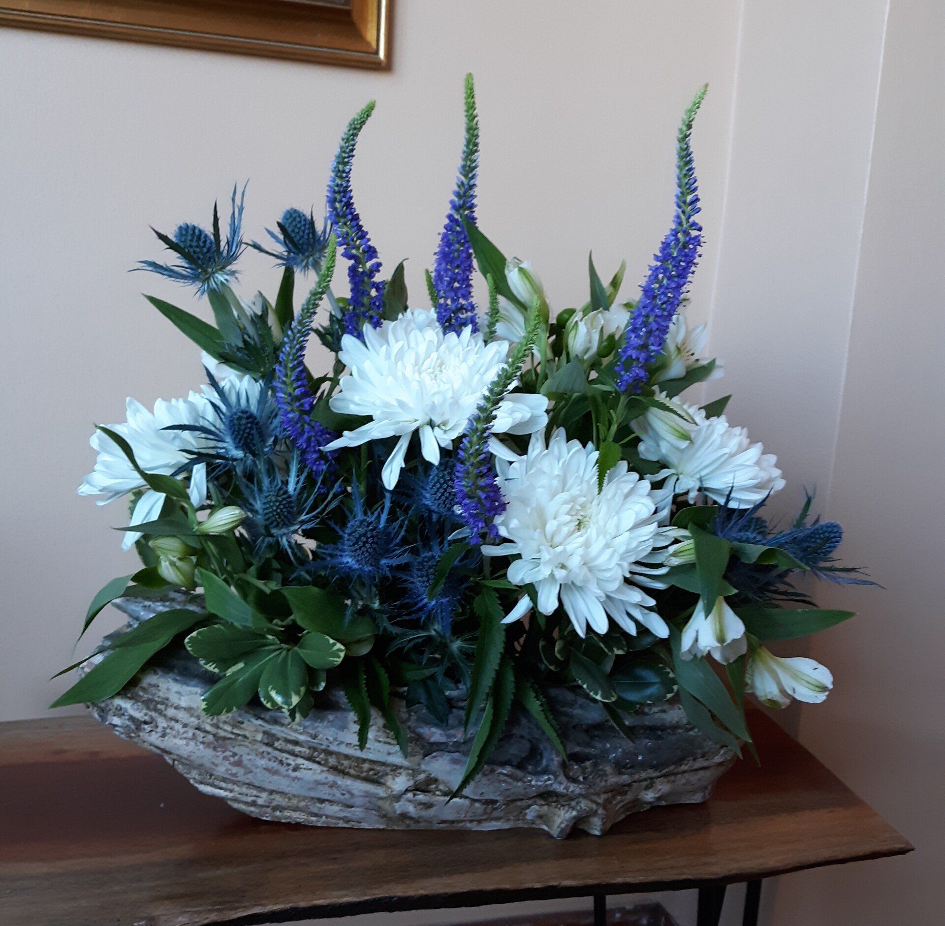 A basket filled with blue and white flowers sits on a table