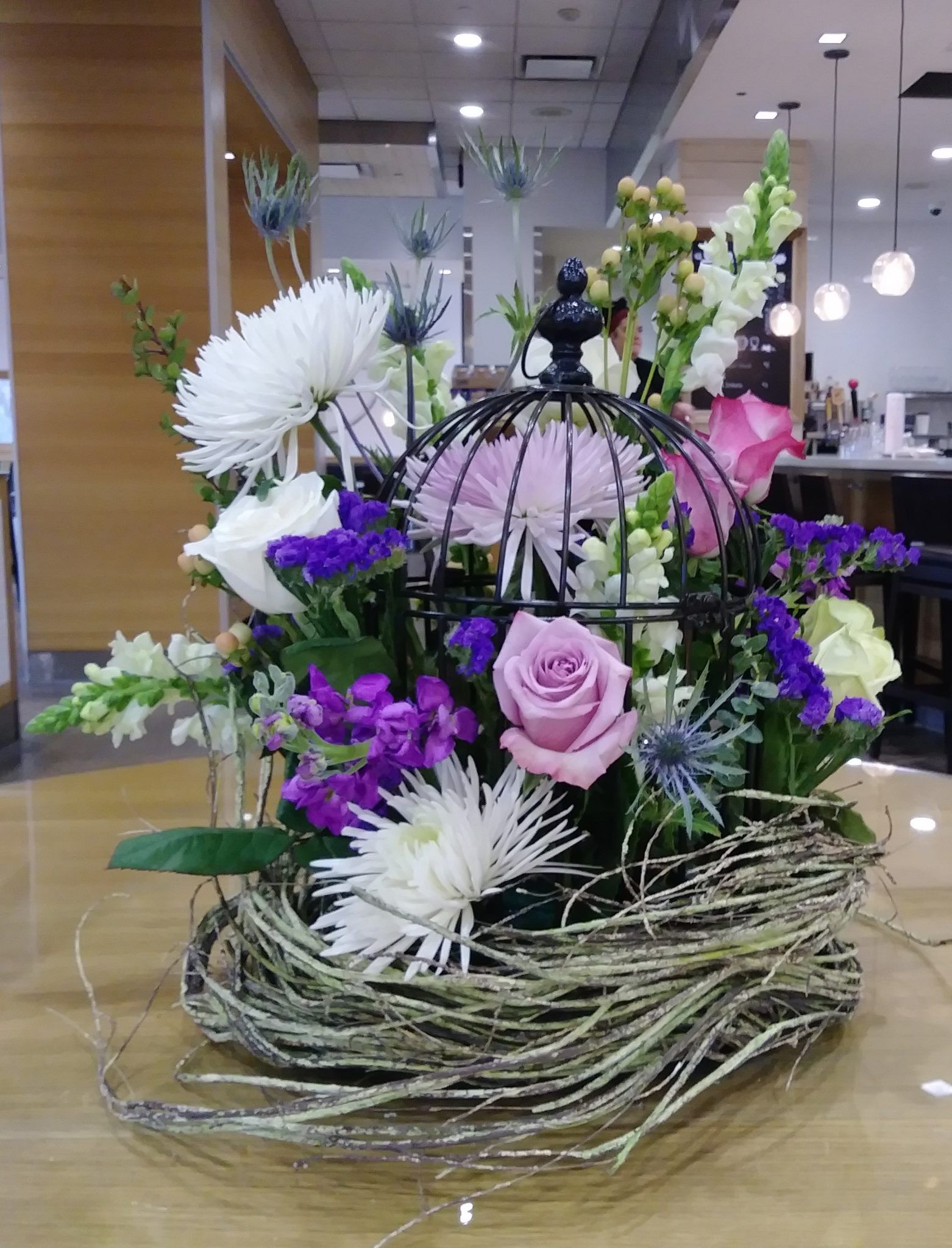 A bird cage filled with flowers is sitting on a table.