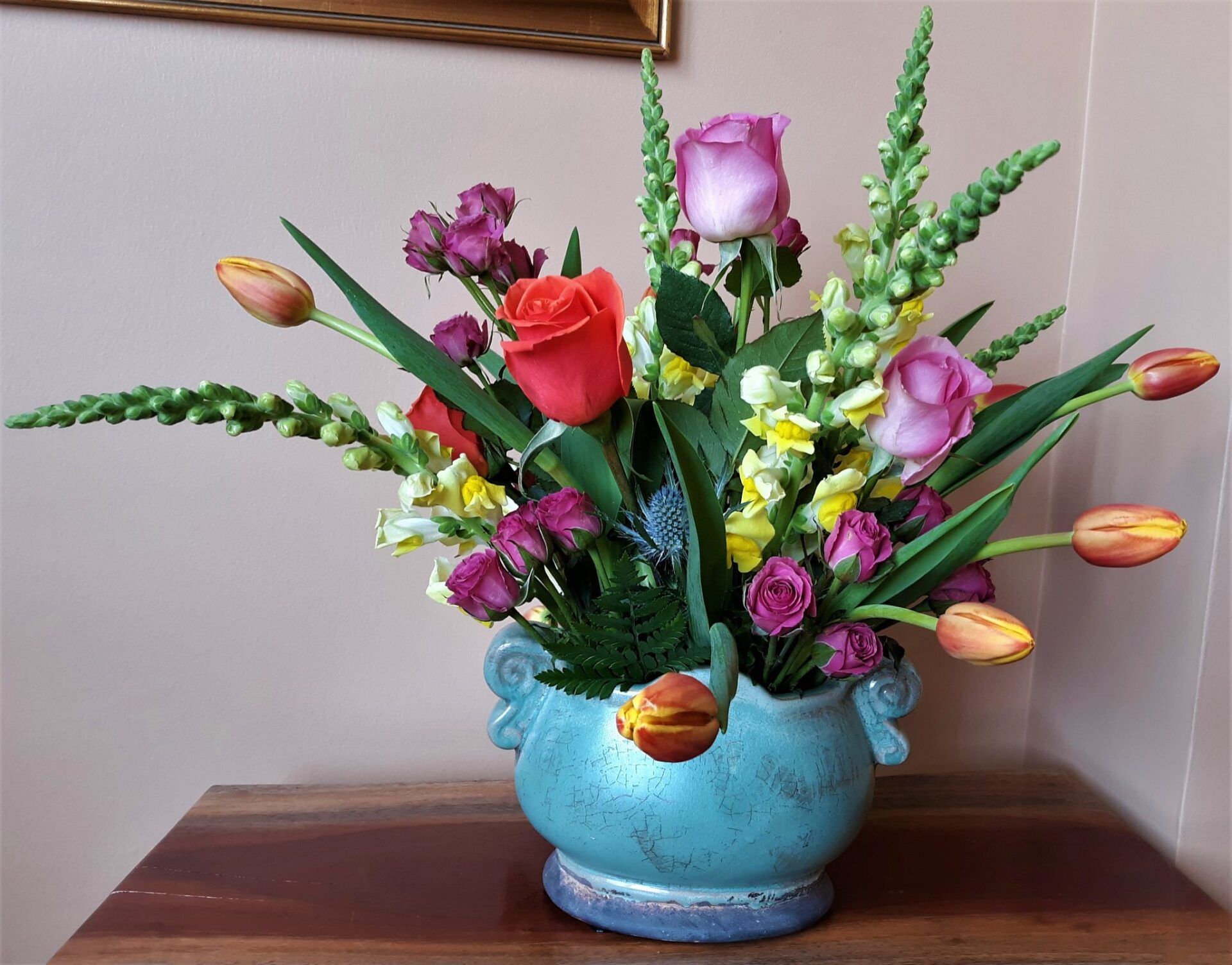A blue vase filled with flowers sits on a table