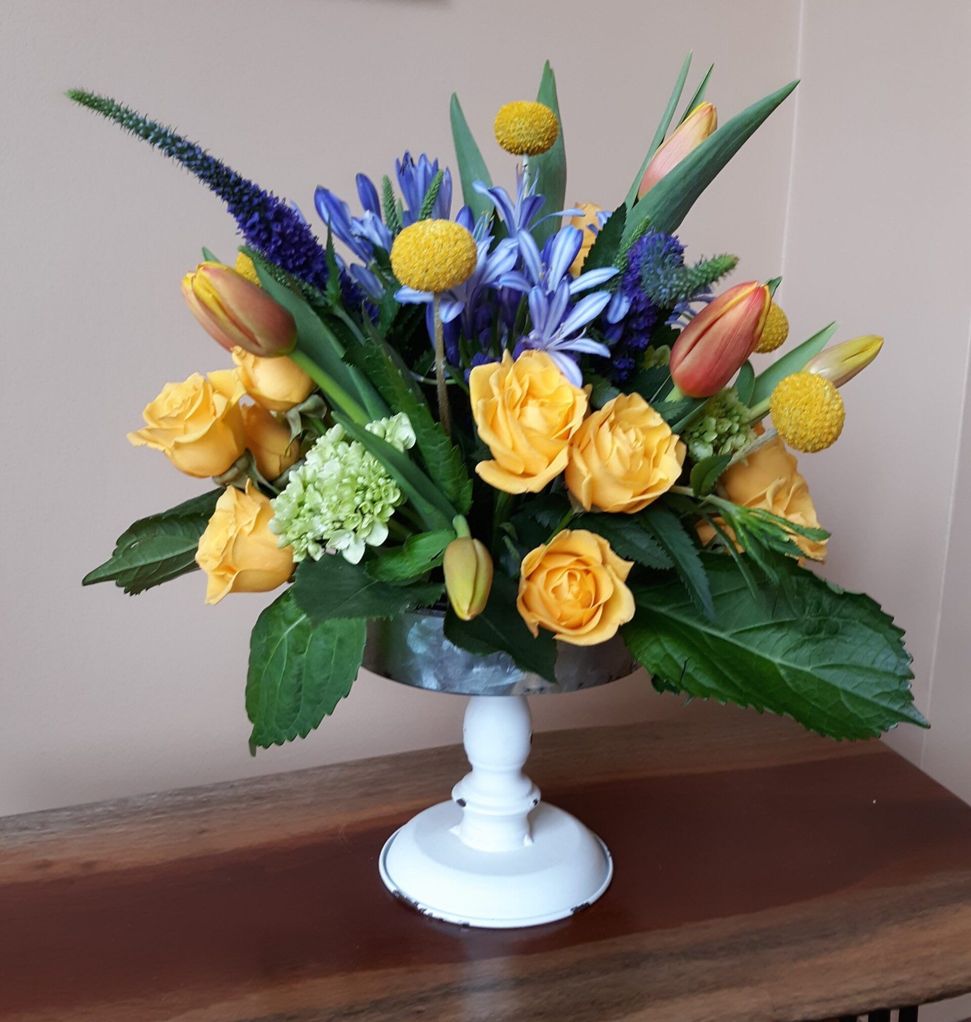 A vase filled with yellow and blue flowers sits on a table