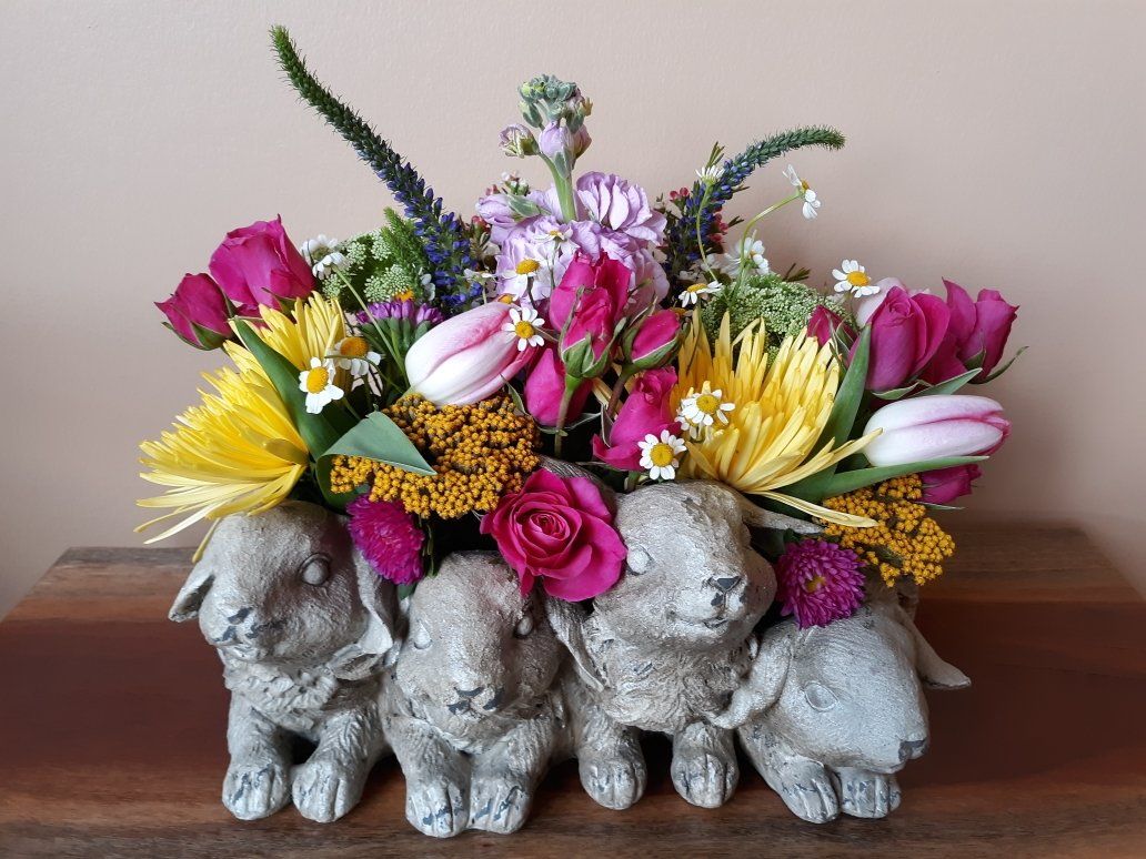 A bunch of rabbits are sitting on a table with flowers in them