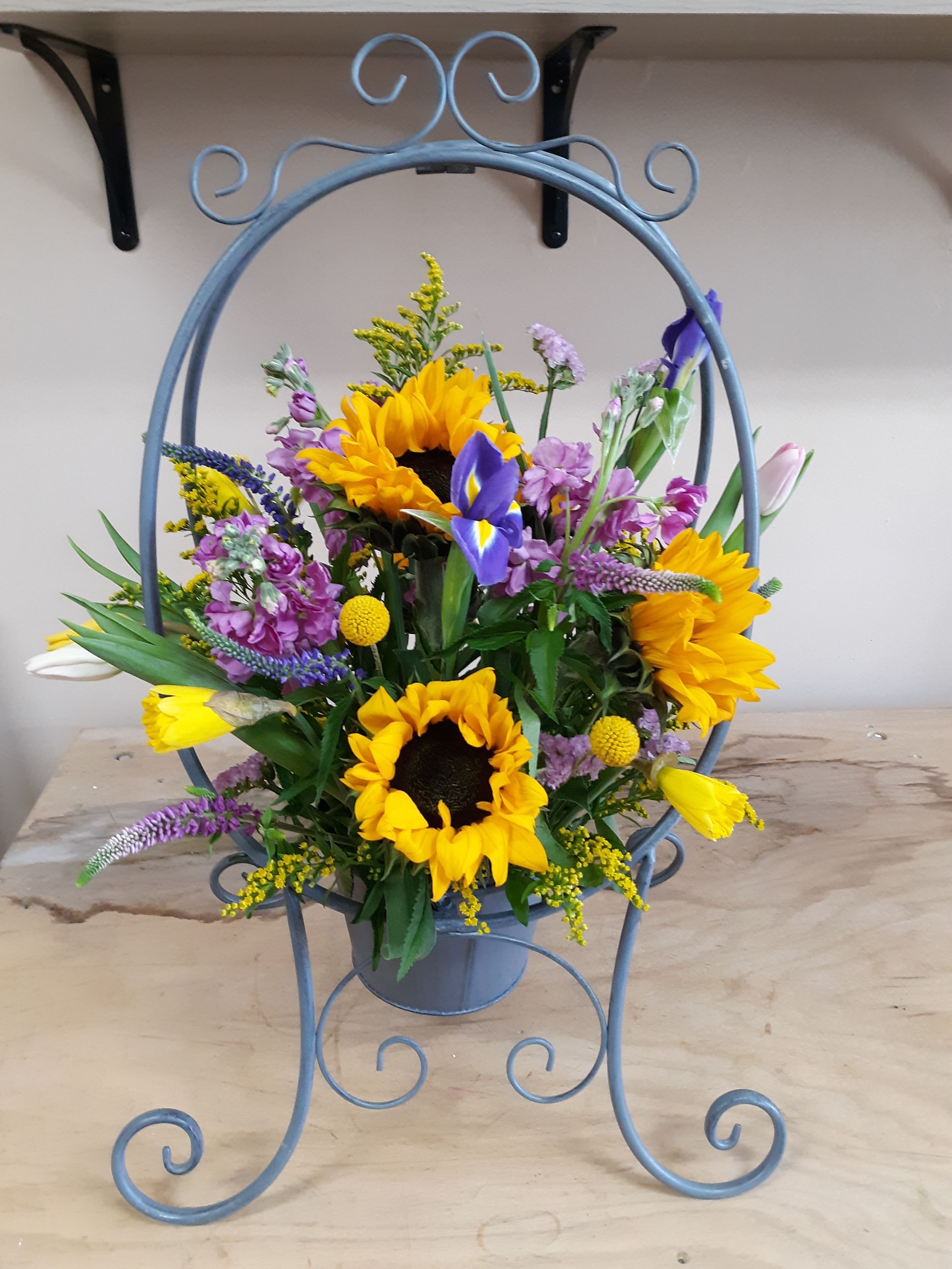 A blue basket filled with sunflowers and other flowers