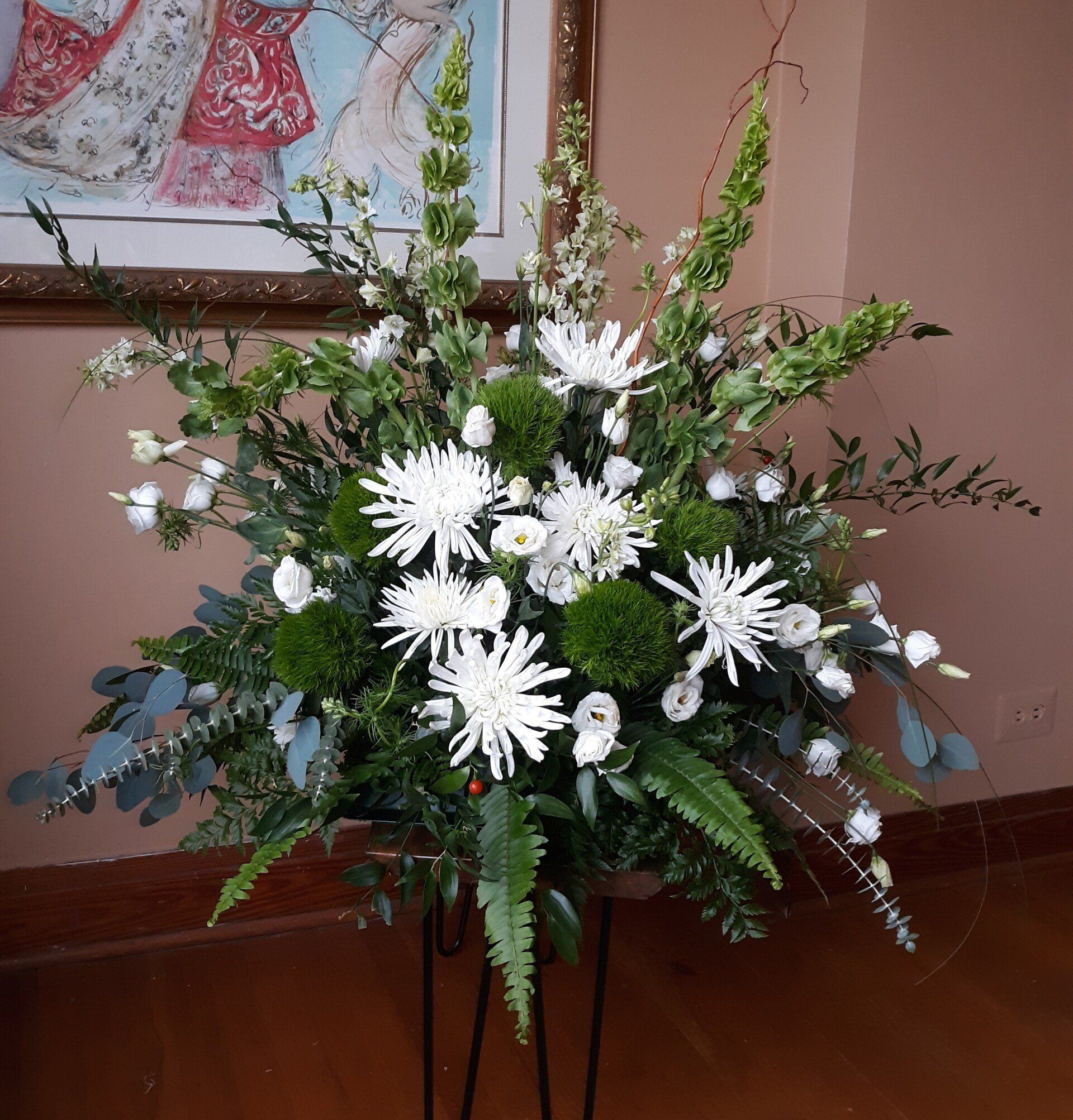 A large bouquet of white and green flowers on a stand