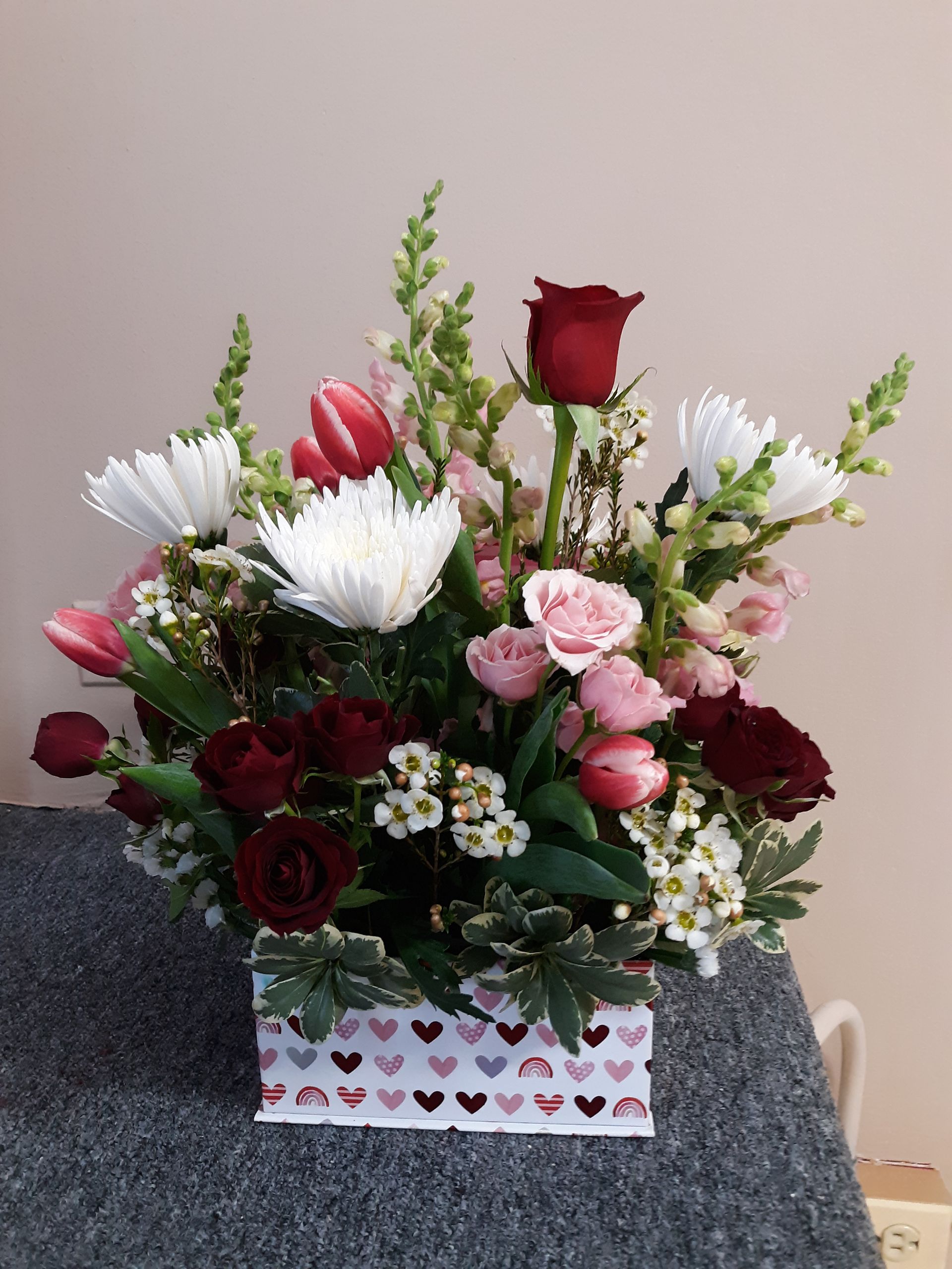 A box filled with flowers is sitting on a table.