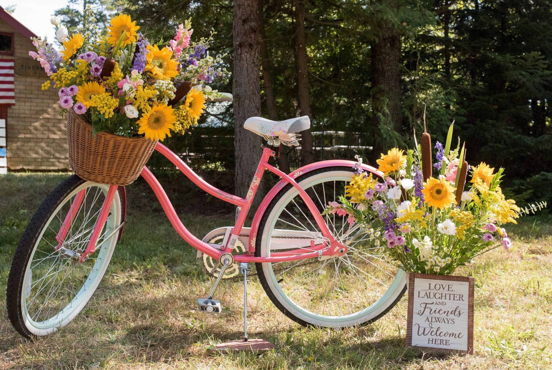 A pink bicycle with a basket full of flowers