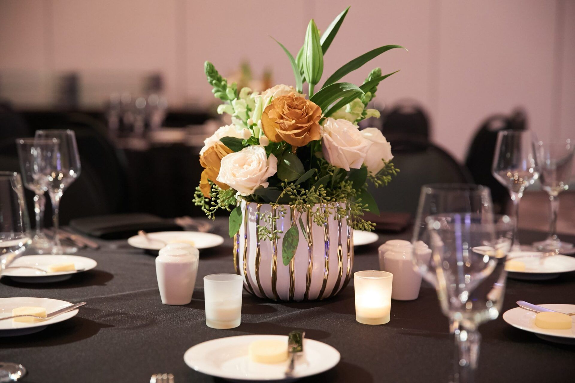 A table with plates , glasses , and a vase of flowers on it.