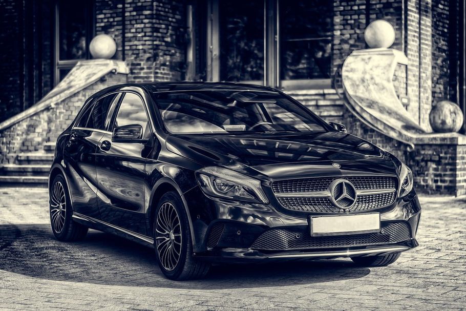 A black and white photo of a mercedes benz parked in front of a brick building.