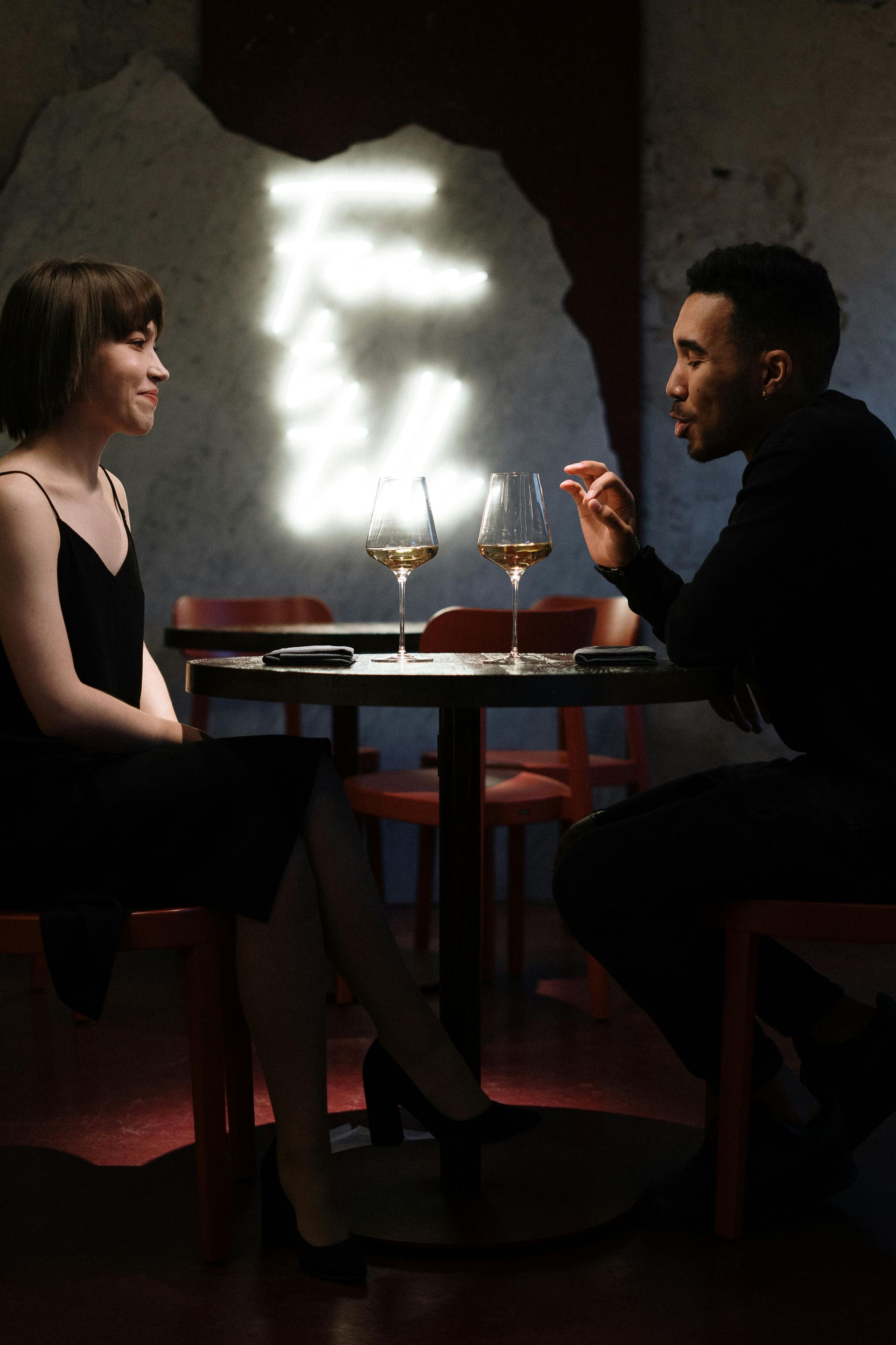 A man and a woman are sitting at a table with wine glasses.