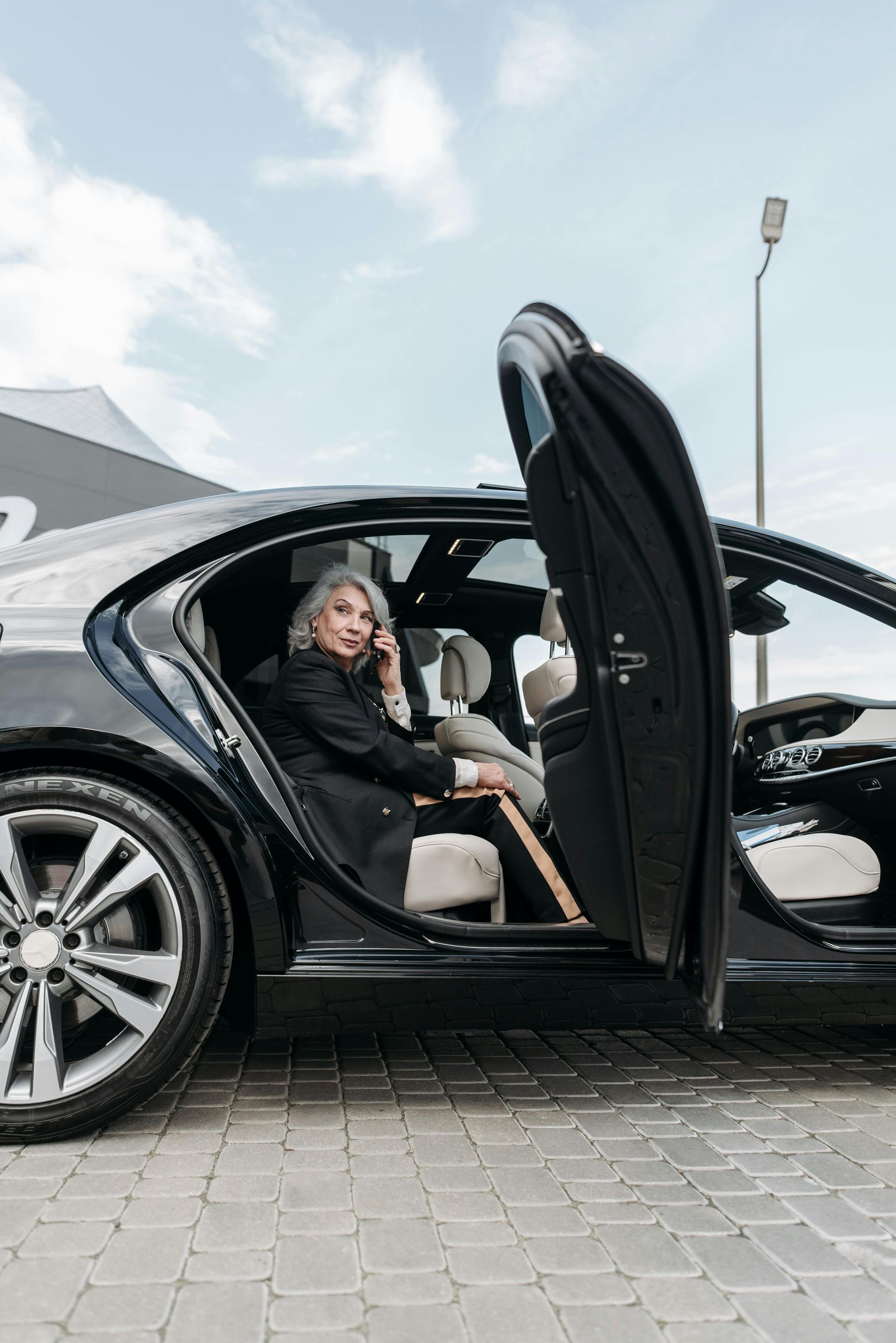 A woman is sitting in the back seat of a car talking on a cell phone.