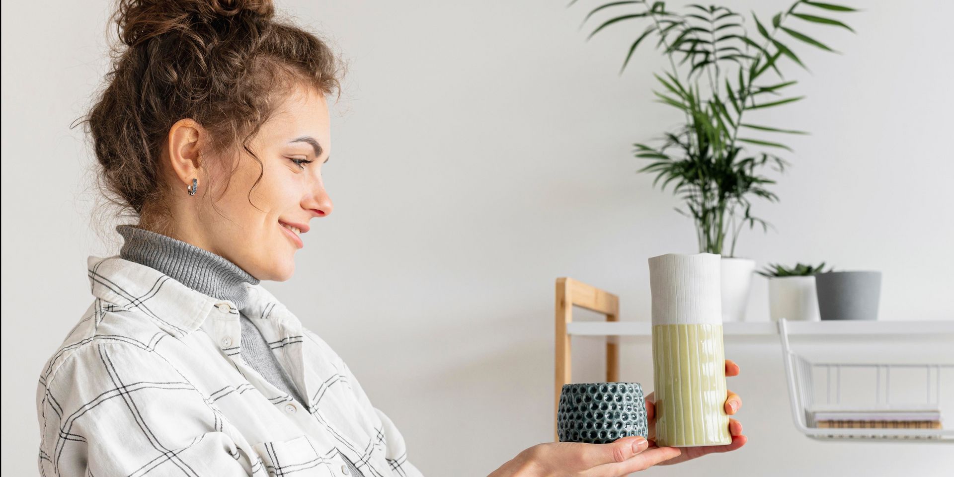 A woman is holding a vase with a plant in it.
