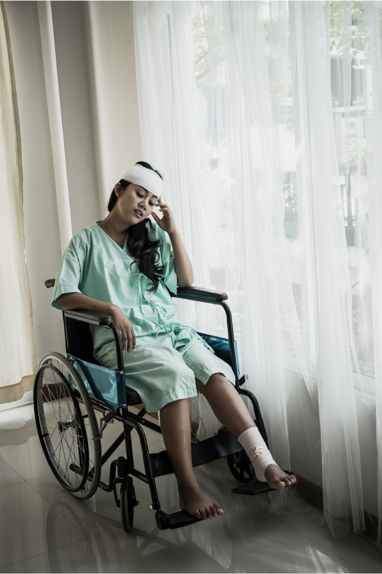 A woman is sitting in a wheelchair with a bandage on her head.