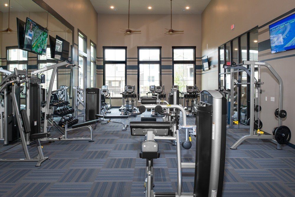A large gym filled with lots of exercise equipment and a television.