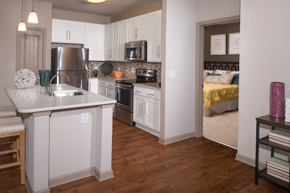 A kitchen with white cabinets , stainless steel appliances , and hardwood floors.