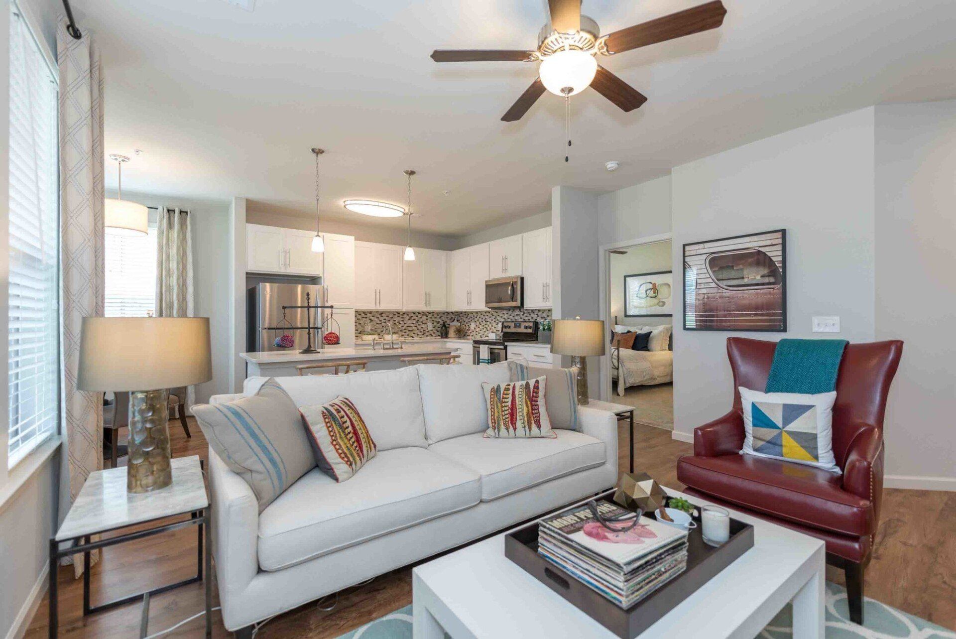 A living room with a couch , chair , coffee table and ceiling fan.