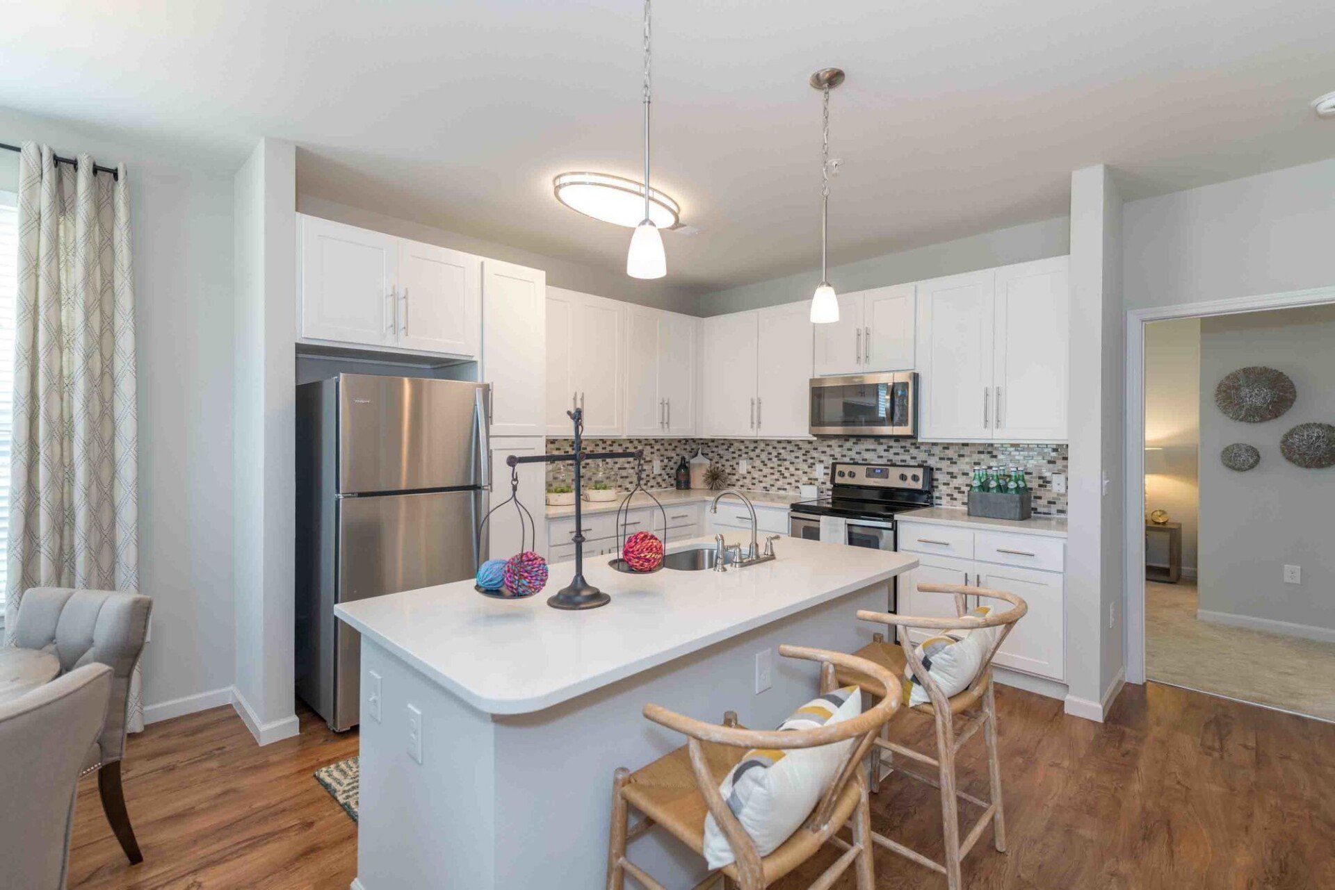 A kitchen with white cabinets , stainless steel appliances , and a large island.