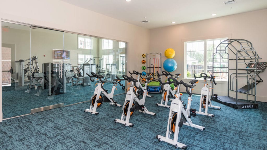 A gym with a lot of exercise bikes and a large mirror.