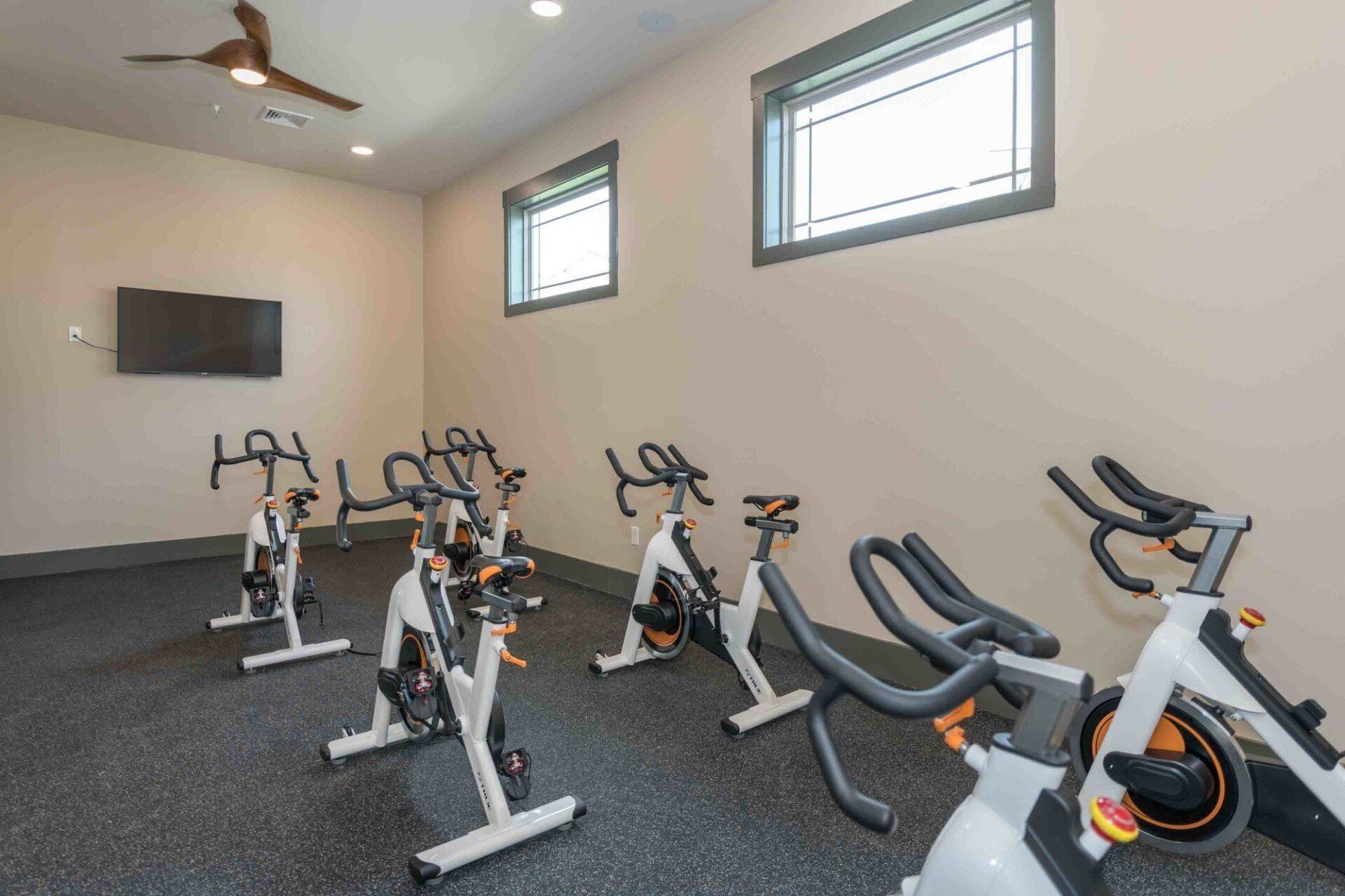 A row of exercise bikes are lined up in a gym.
