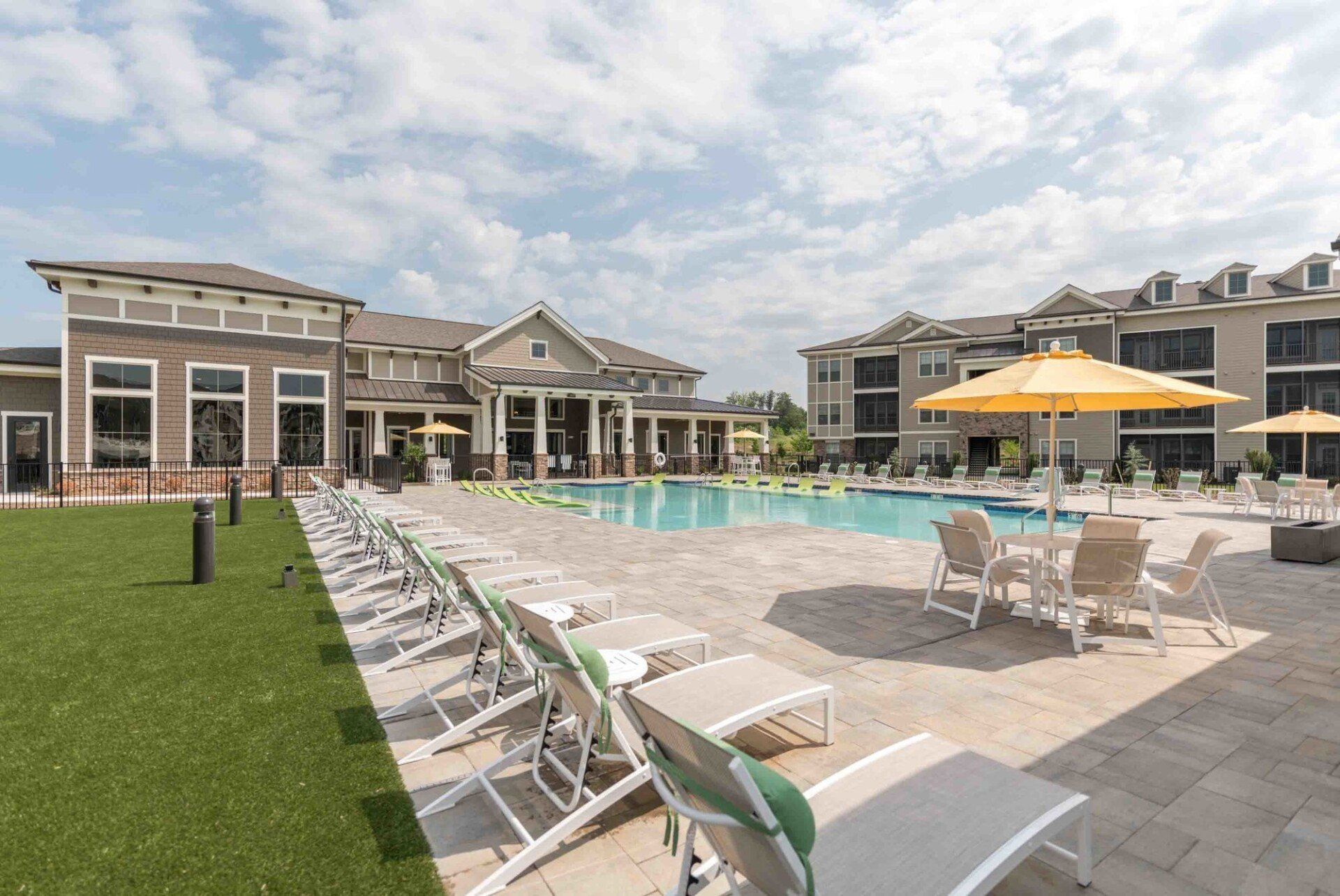 A large swimming pool surrounded by chairs and umbrellas in front of a large building.