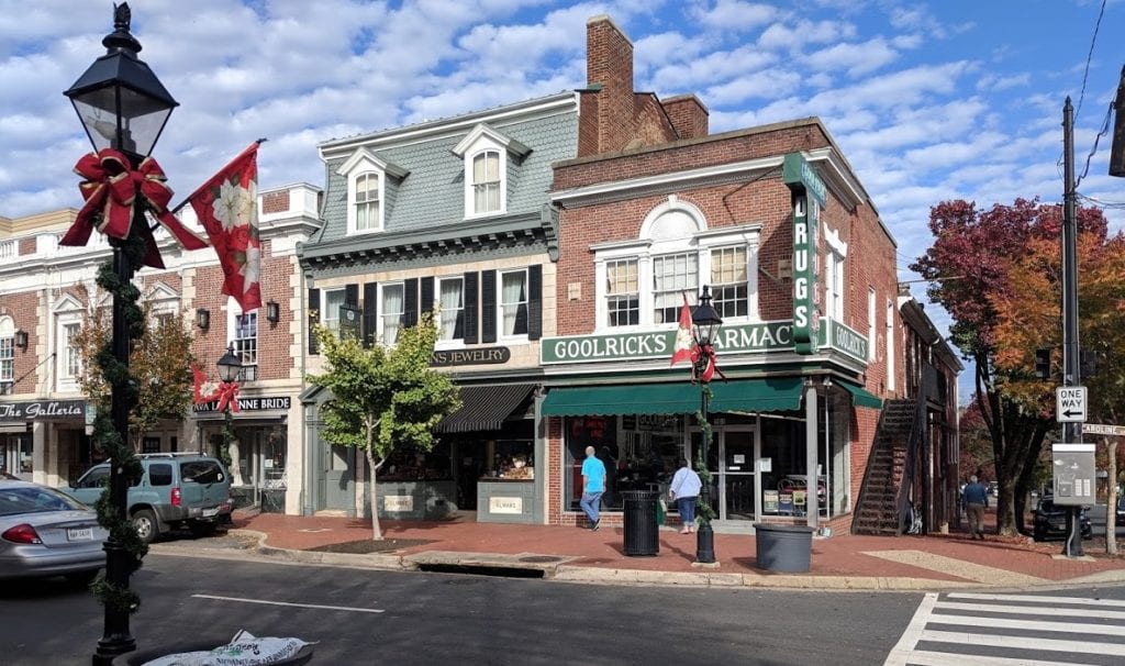 A brick building with a green awning is on the corner of a street.