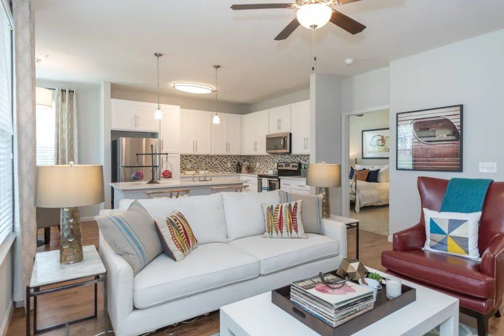 A living room with a white couch and a red chair