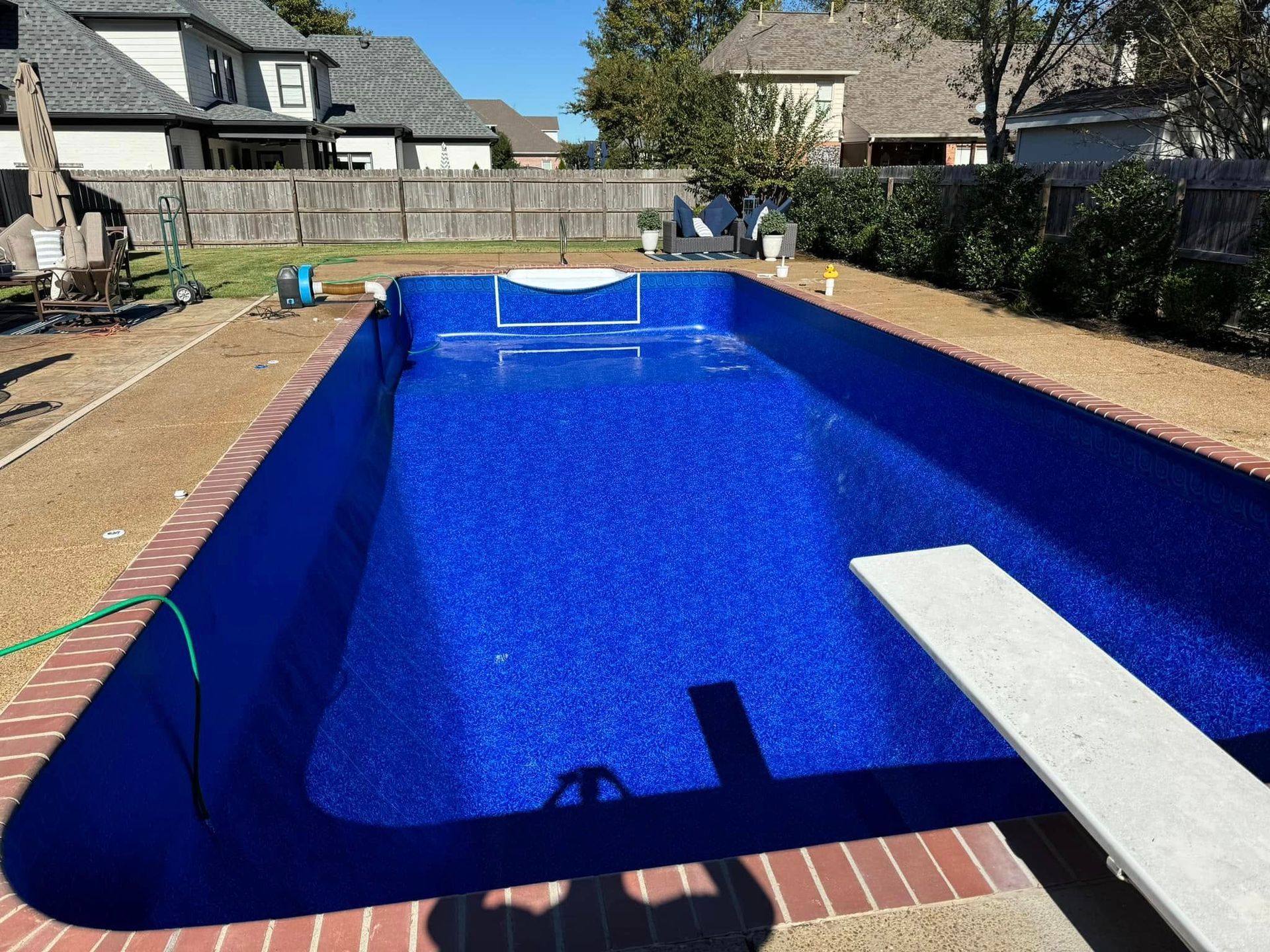 A large blue swimming pool with a diving board in the middle