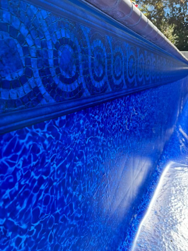 A blue swimming pool with a mosaic design on the side.