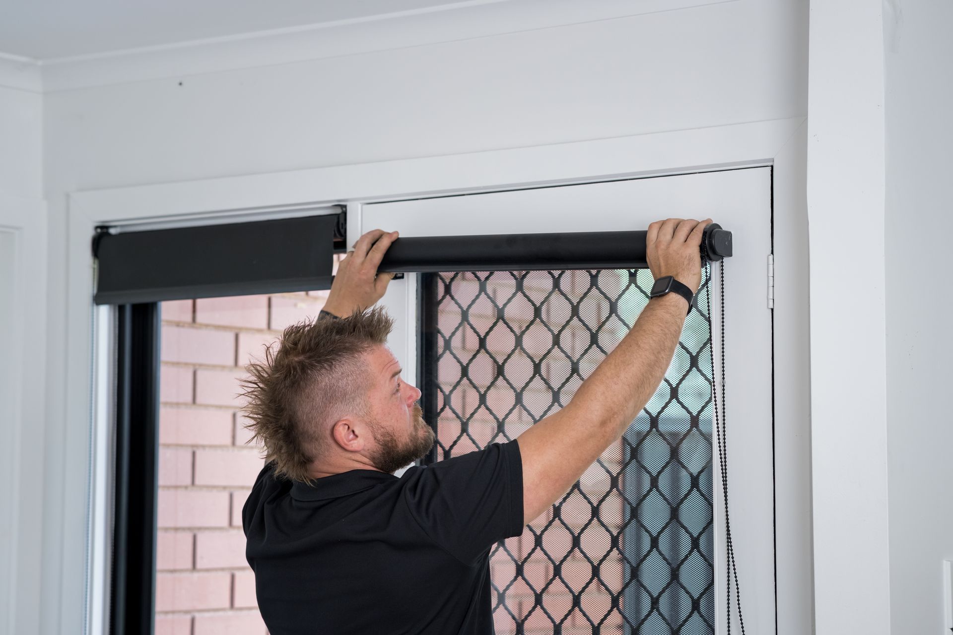 A Man Installs A Black Roller Blind - 2easy Property Maintenance in Bendigo, VIC