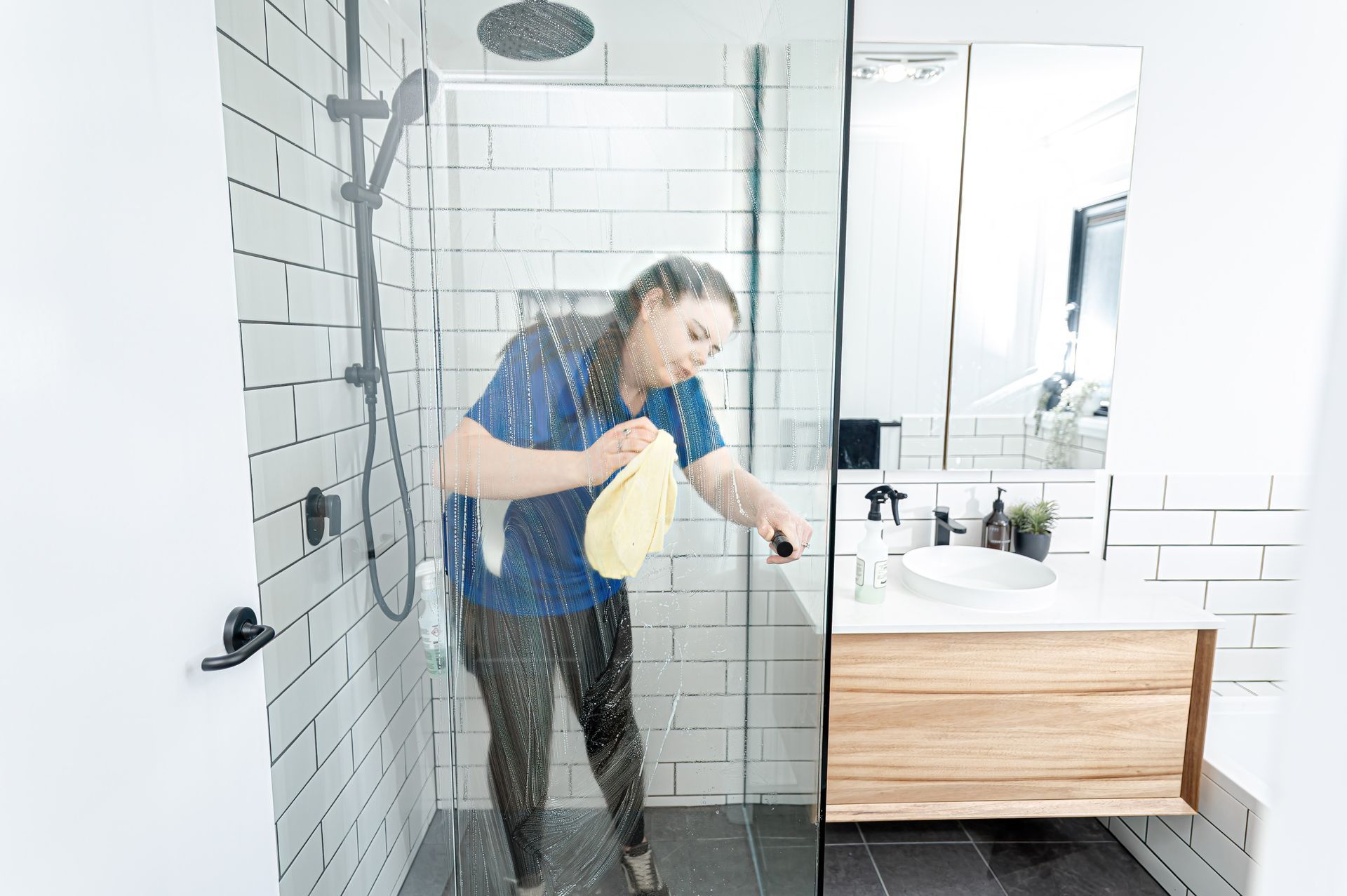 A Woman Is Cleaning A Shower Door In A Bathroom — 2easy Cleaning in Bendigo, VIC