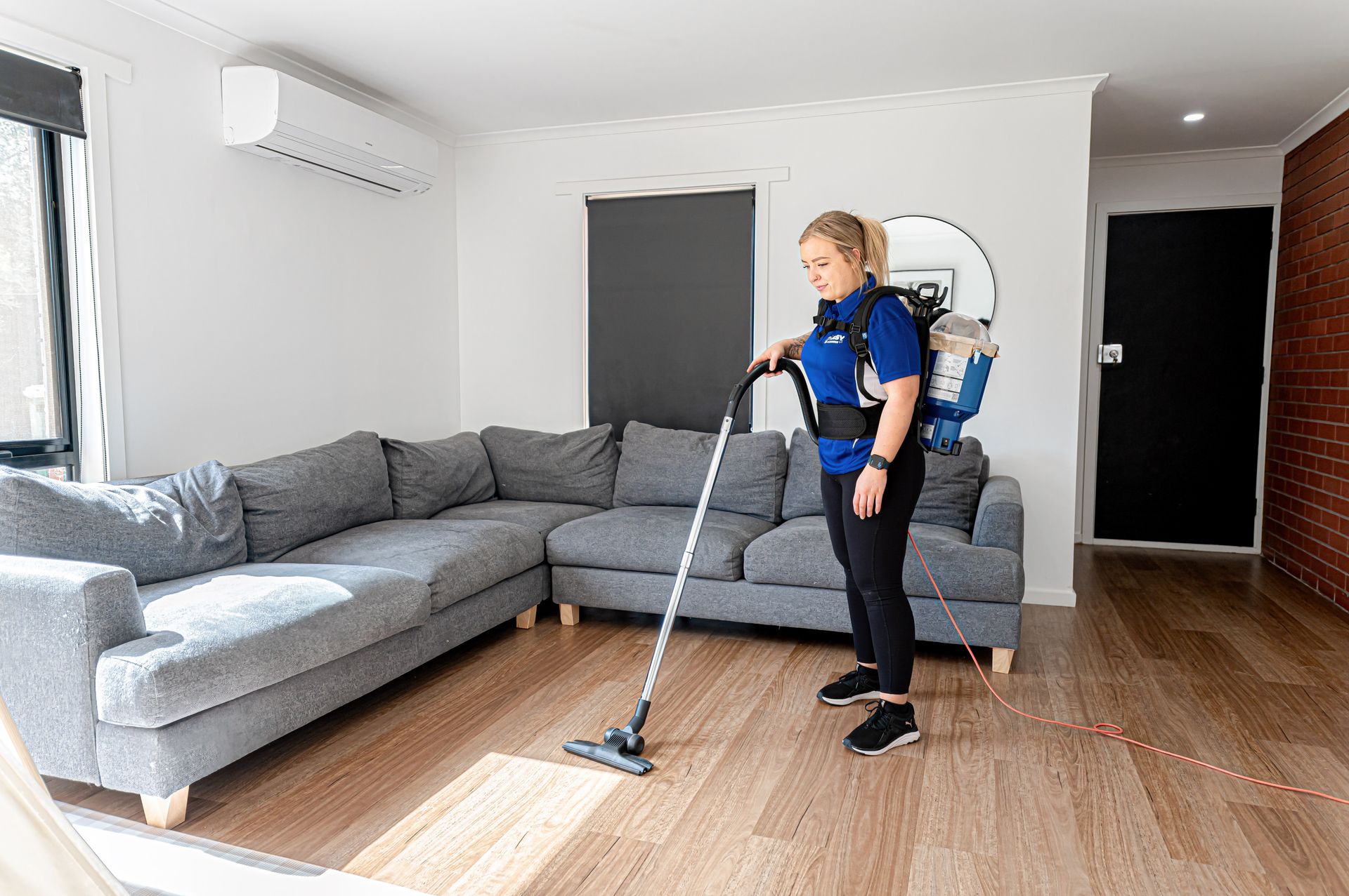 A Woman Is Cleaning The Floor Of A Living Room With A Vacuum Cleaner — 2easy Cleaning in Bendigo, VIC