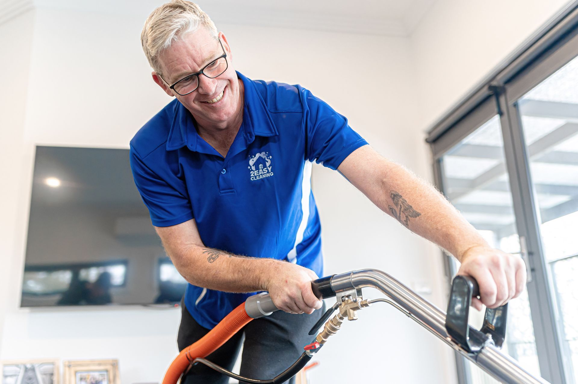 A Man In A Blue Shirt Is Using A Vacuum Cleaner In A Living Room — 2easy Cleaning in Bendigo, VIC