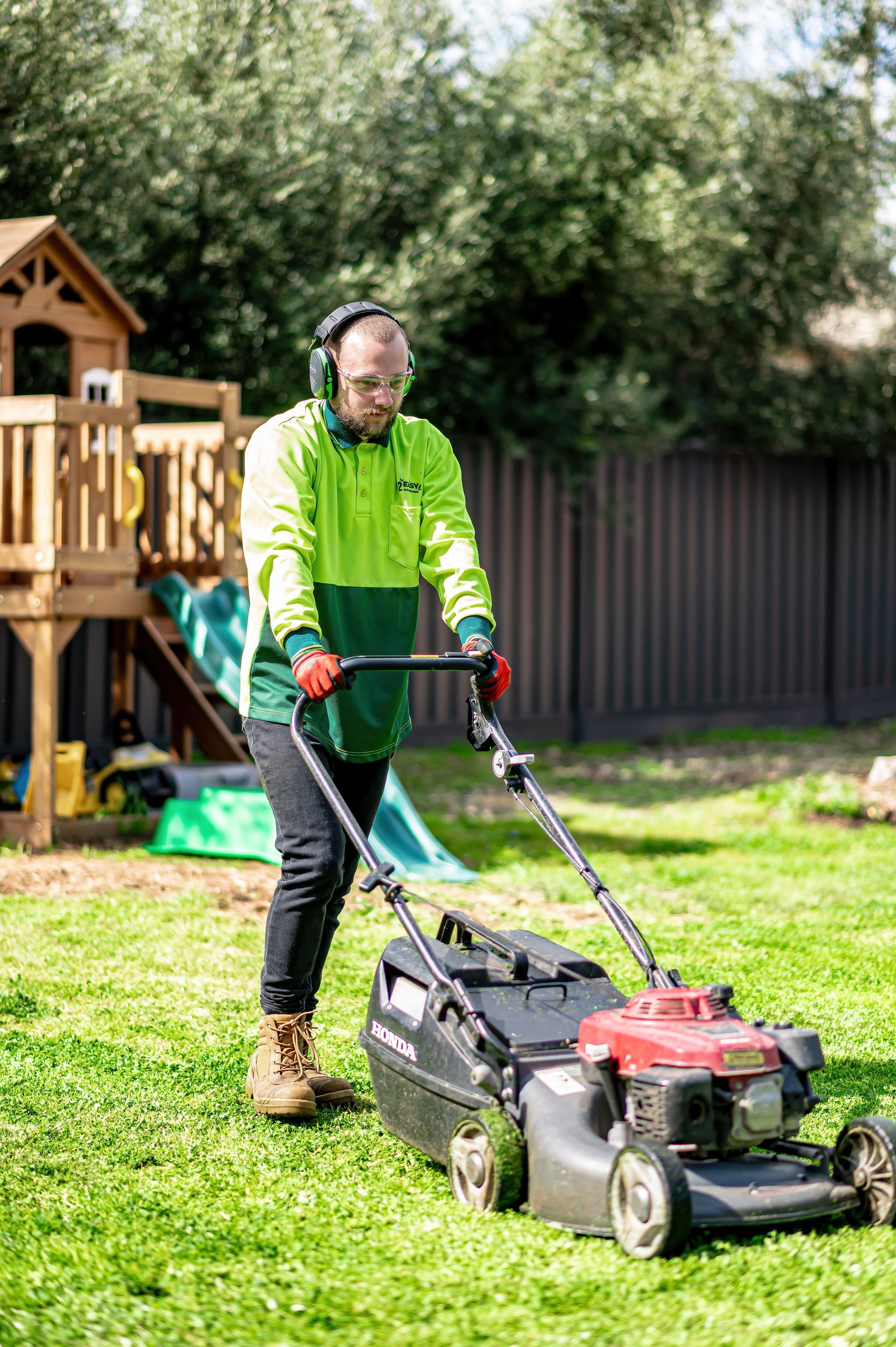 A Man Is Using A Lawn Mower To Cut The Grass In A Backyard — 2easy Cleaning in Bendigo, VIC