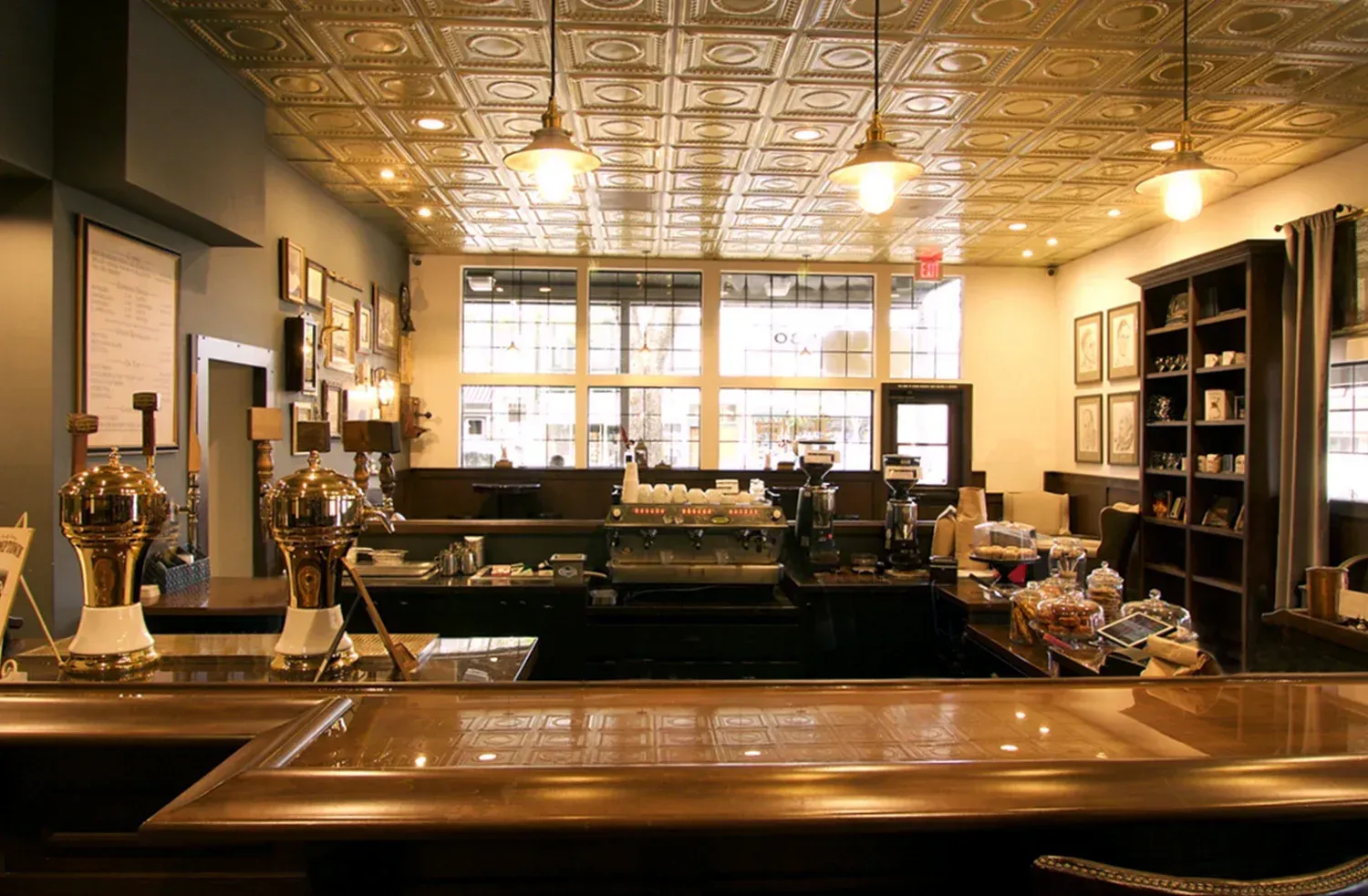 Coffee shop interior with a copper bar, tin ceiling, and large window.