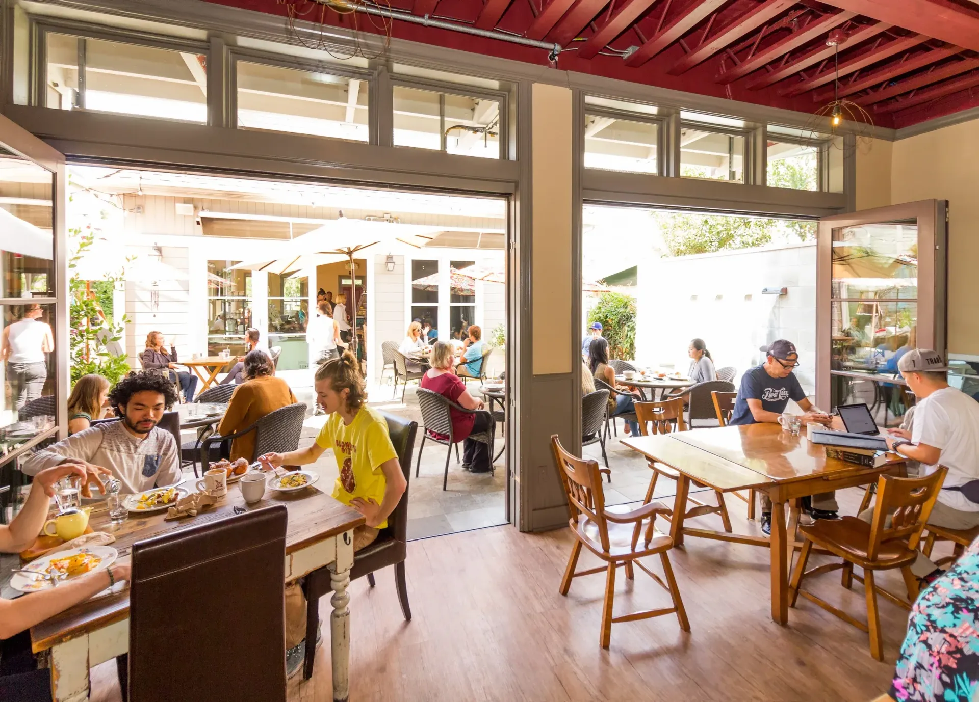 Restaurant interior with indoor and outdoor seating; people eating and socializing.