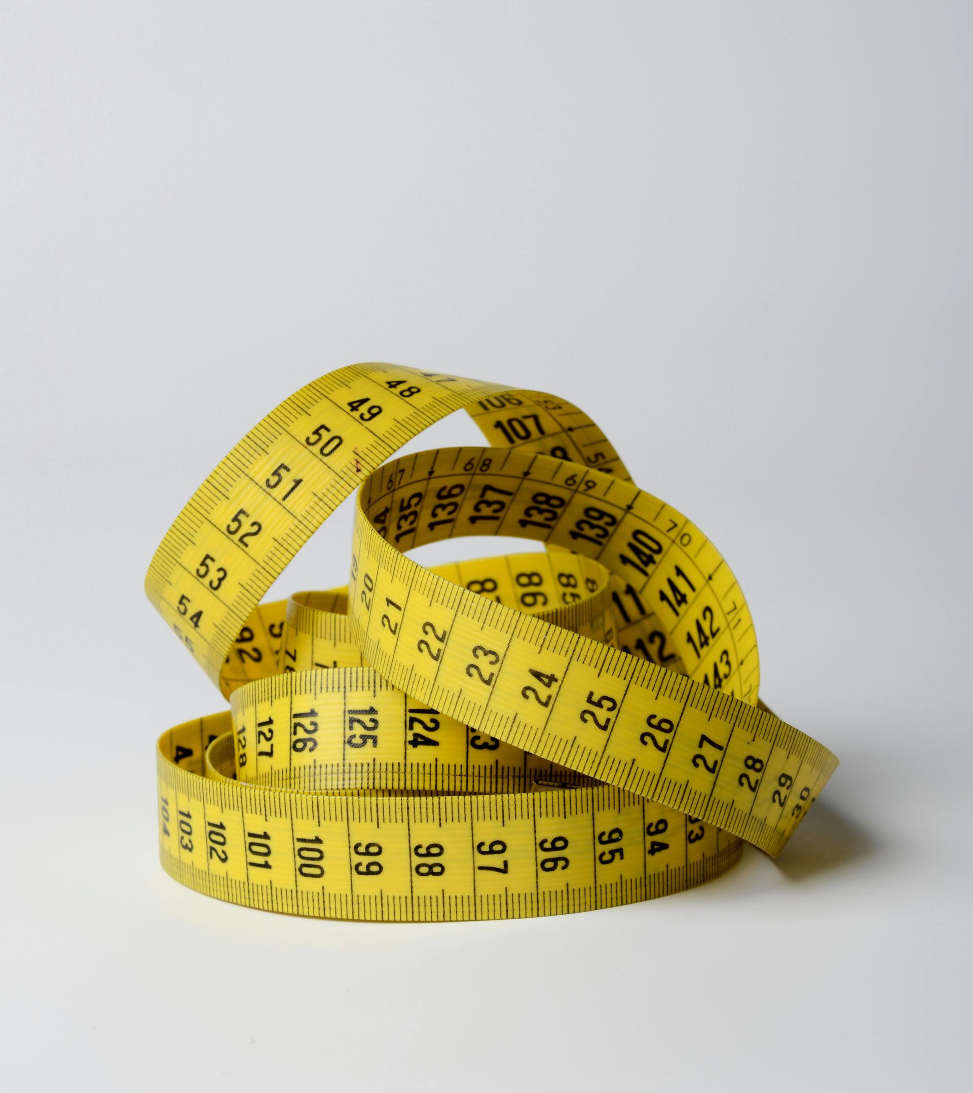 Yellow coiled measuring tape with black markings, on a white background.