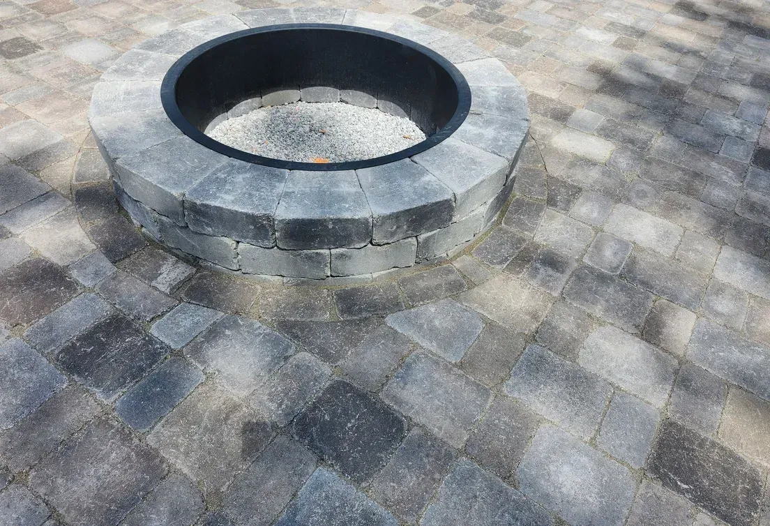 A fire pit is sitting on top of a brick patio.