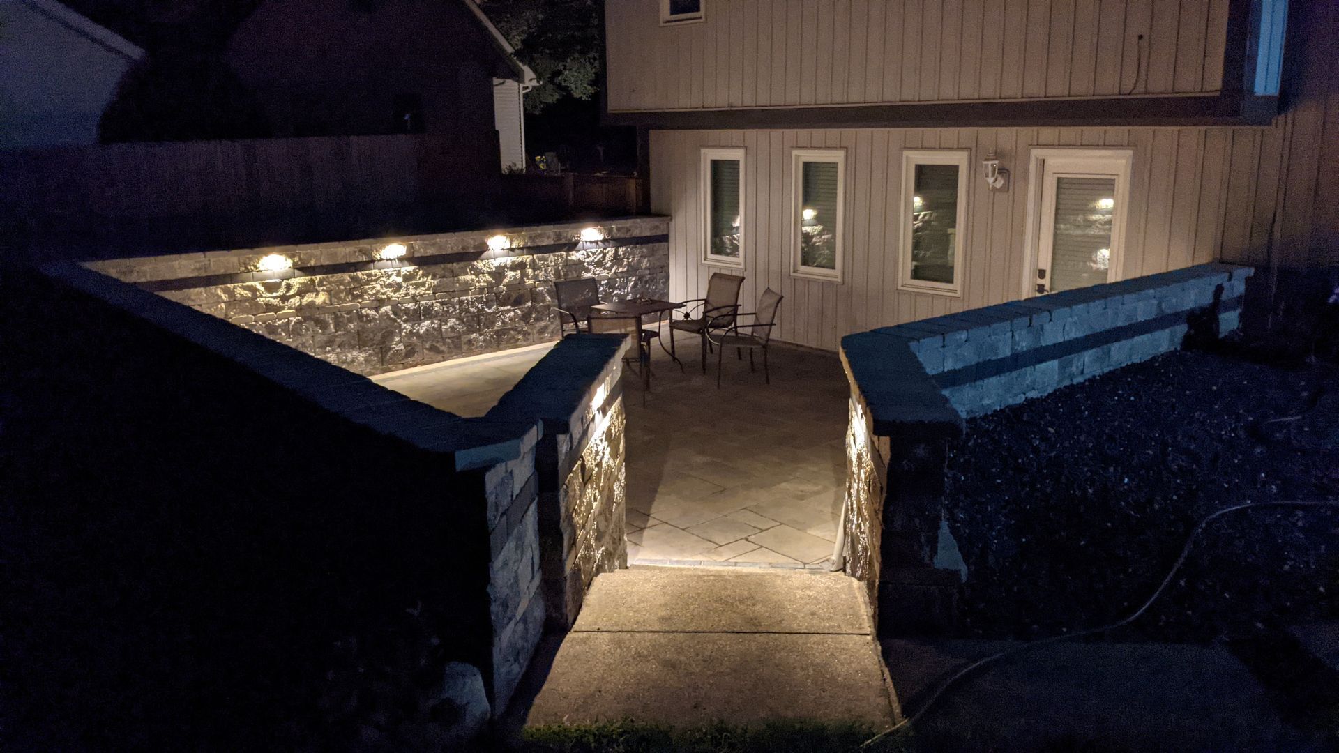 A patio with tables and chairs is lit up at night.
