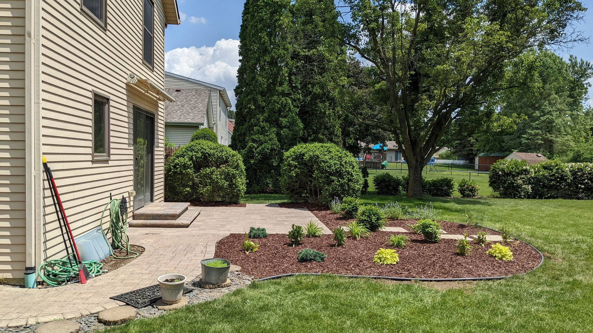 A house with a patio and a garden in front of it.