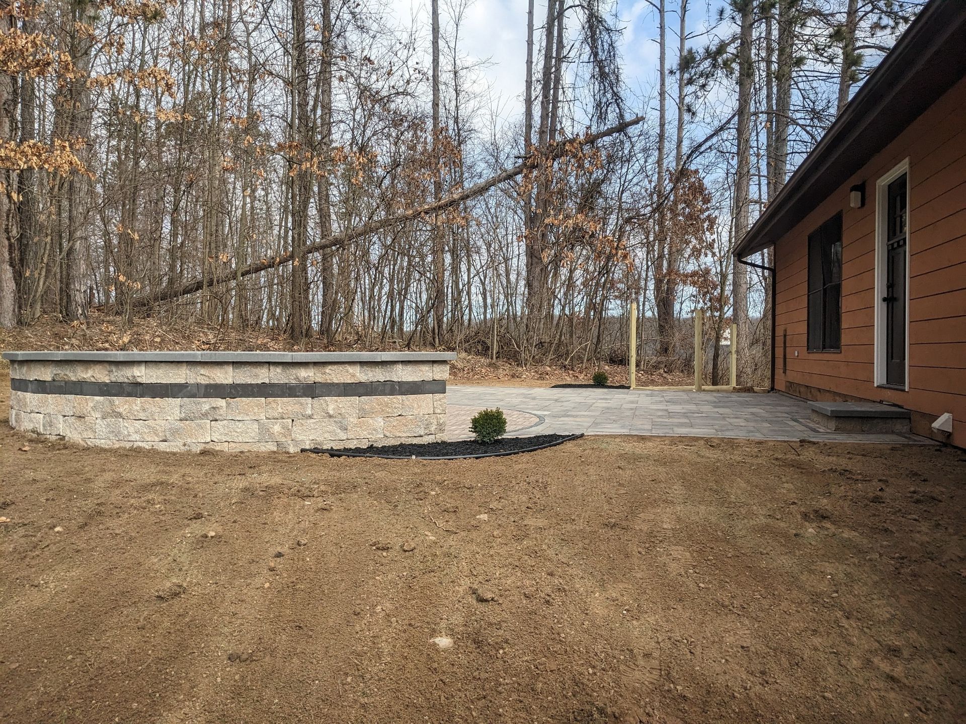 A house with a patio in front of it and trees in the background.