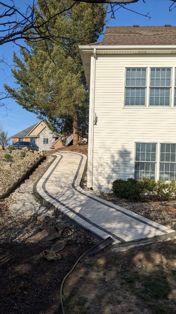 A white house with a concrete walkway leading to it.