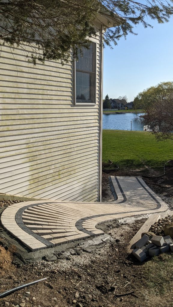 A sidewalk is being built in front of a house with a lake in the background.