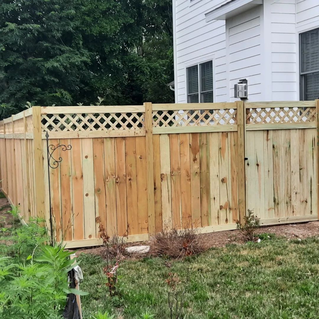 A wooden fence is in front of a white house.