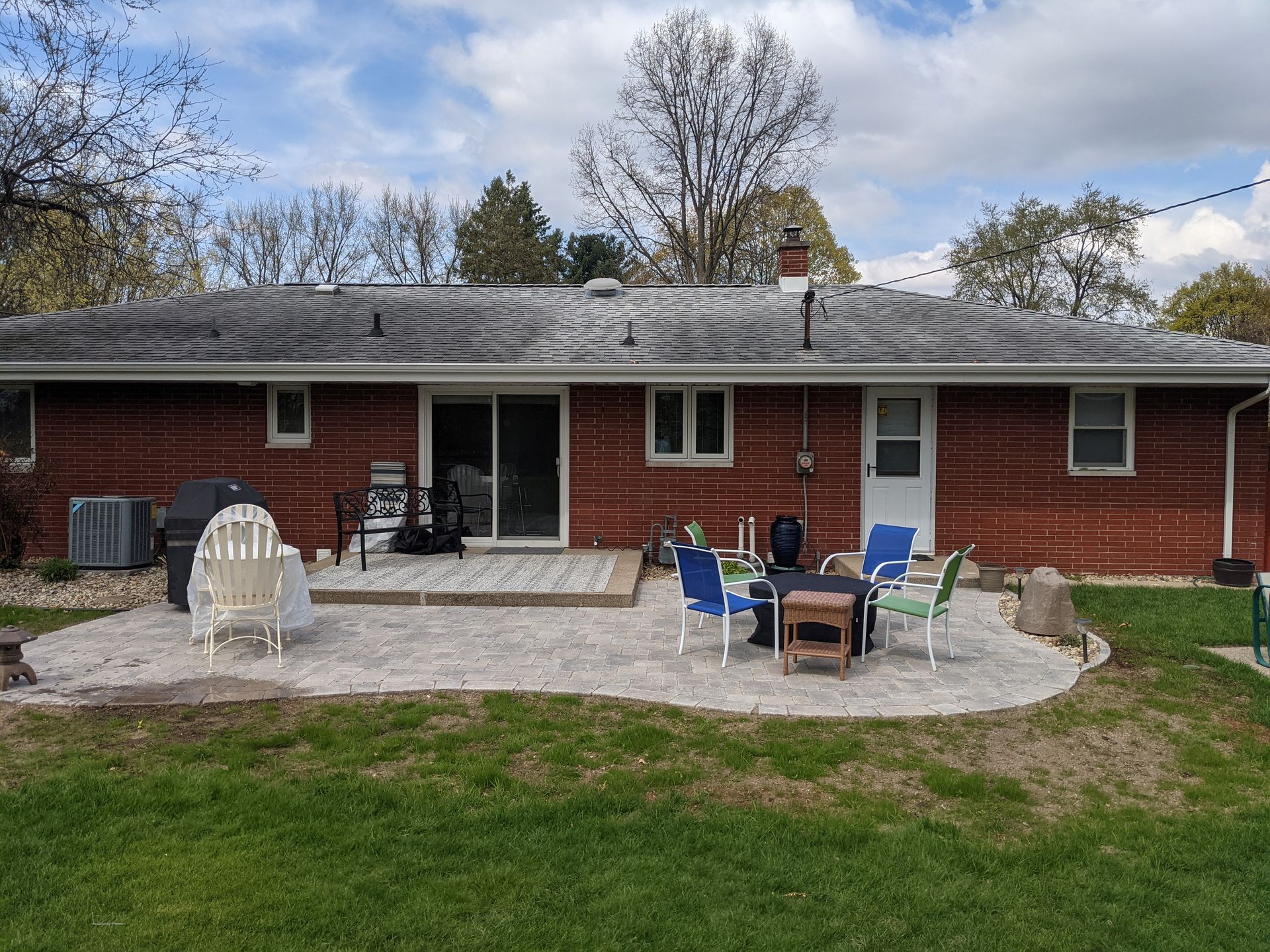 A brick house with a patio and chairs in front of it.