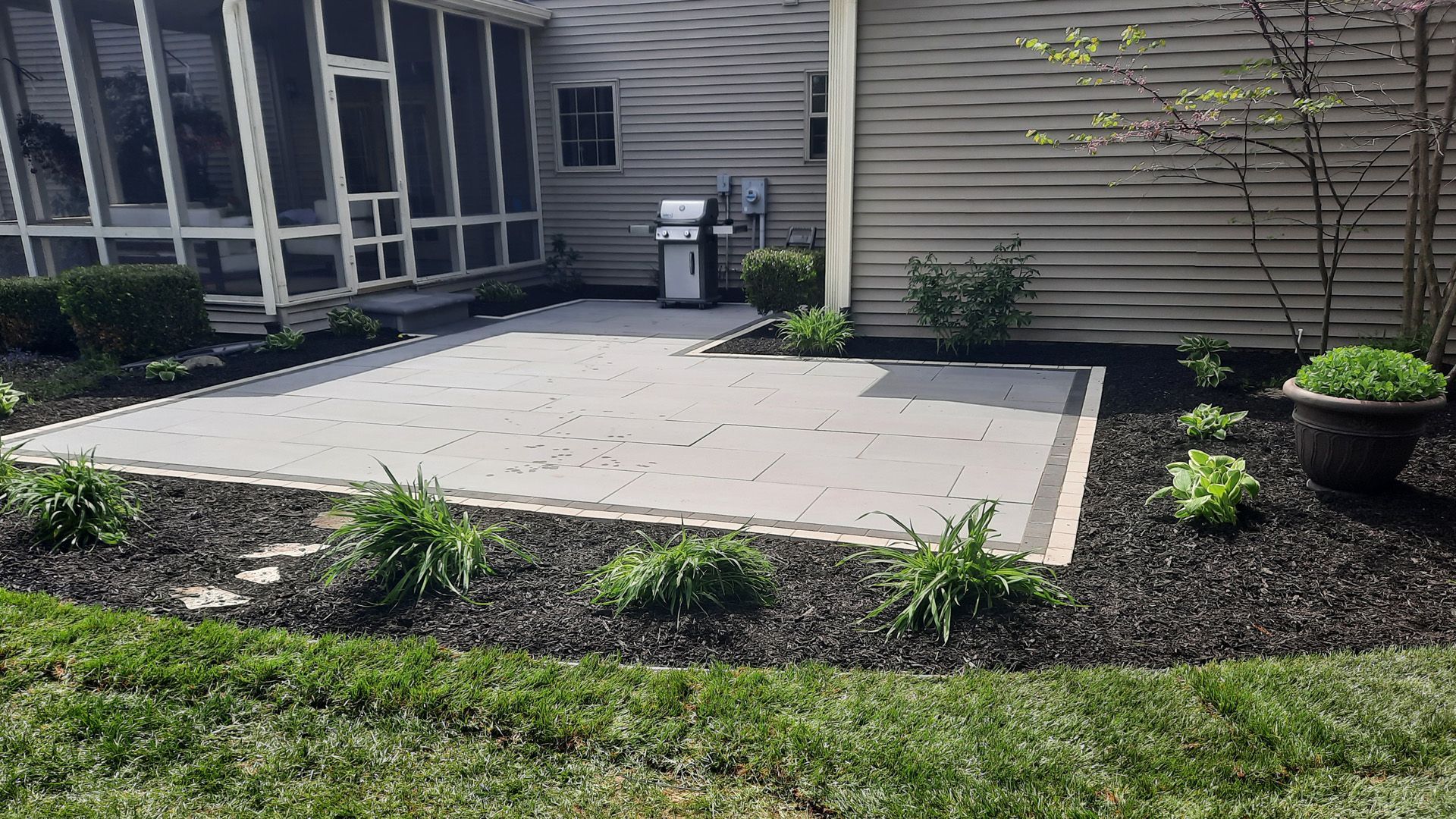 A patio with a grill and a screened in porch