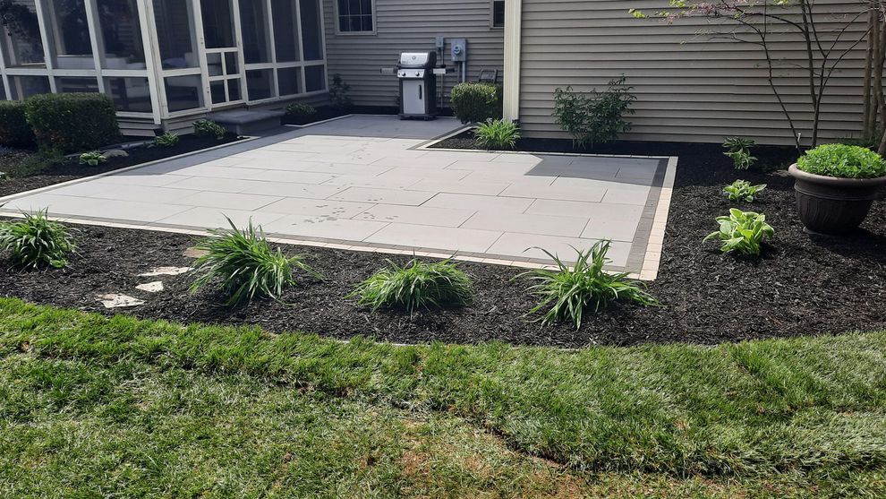 A patio with a grill and a screened in porch in the backyard of a house.
