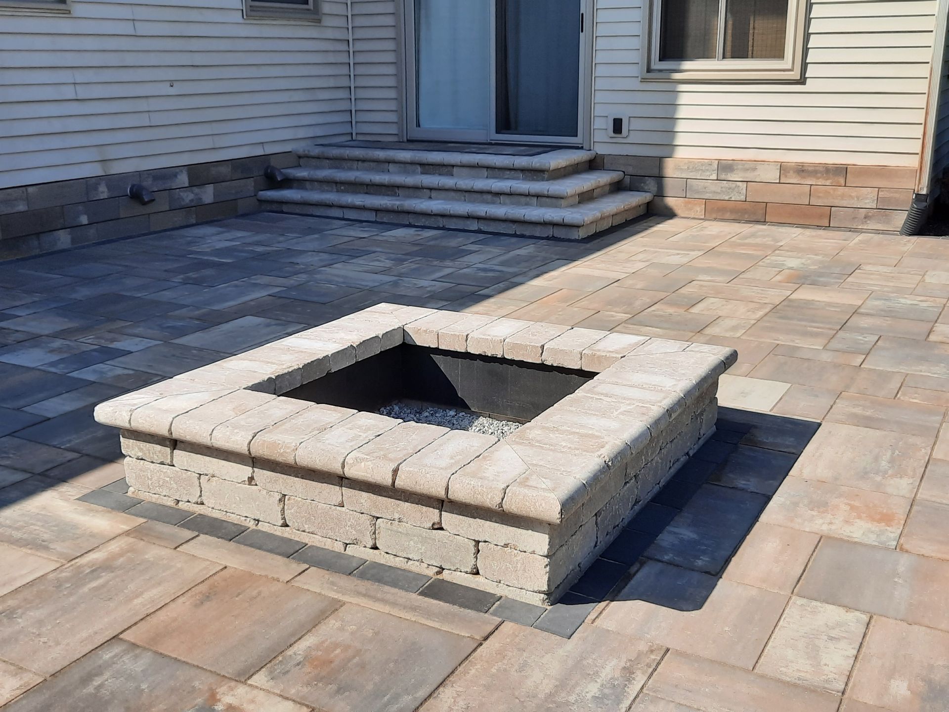 A fire pit is sitting on a patio in front of a house.