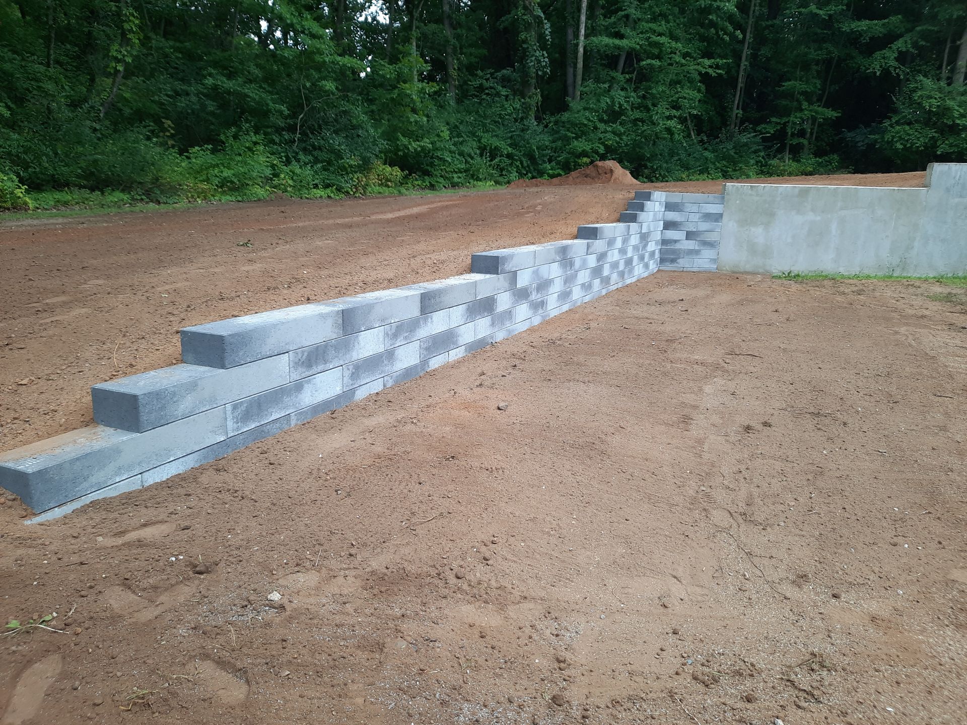 A concrete wall is sitting in the middle of a dirt field