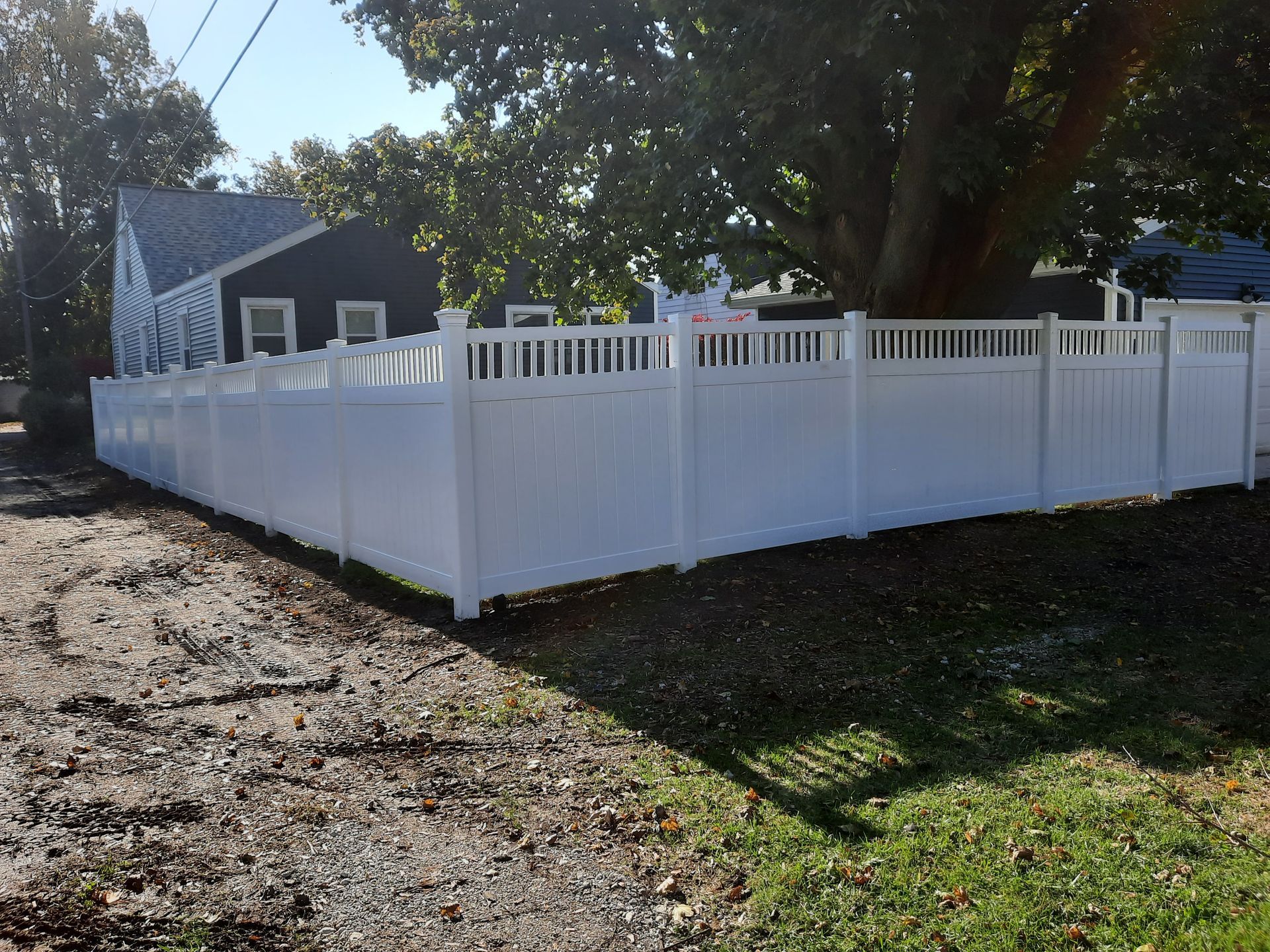 A white fence surrounds a grassy yard in front of a house.