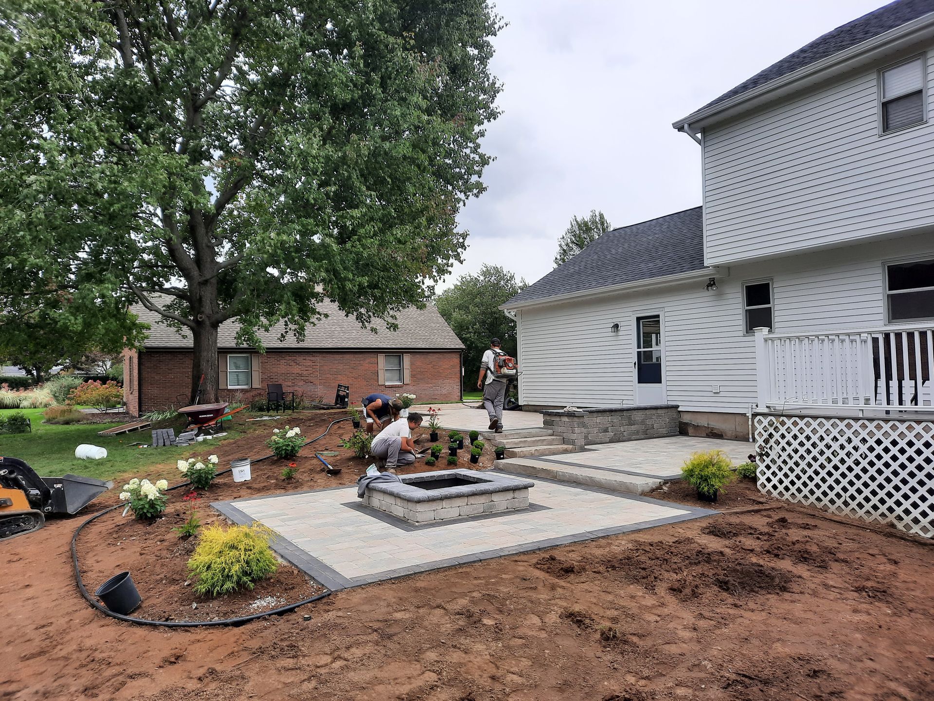 A fire pit is being built in the backyard of a house.
