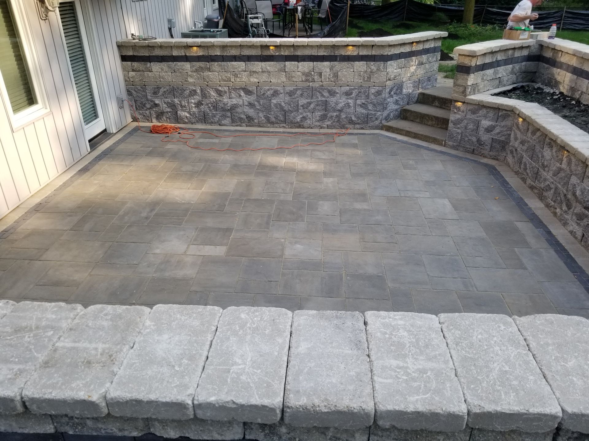 A patio with a stone wall and steps in front of a house.