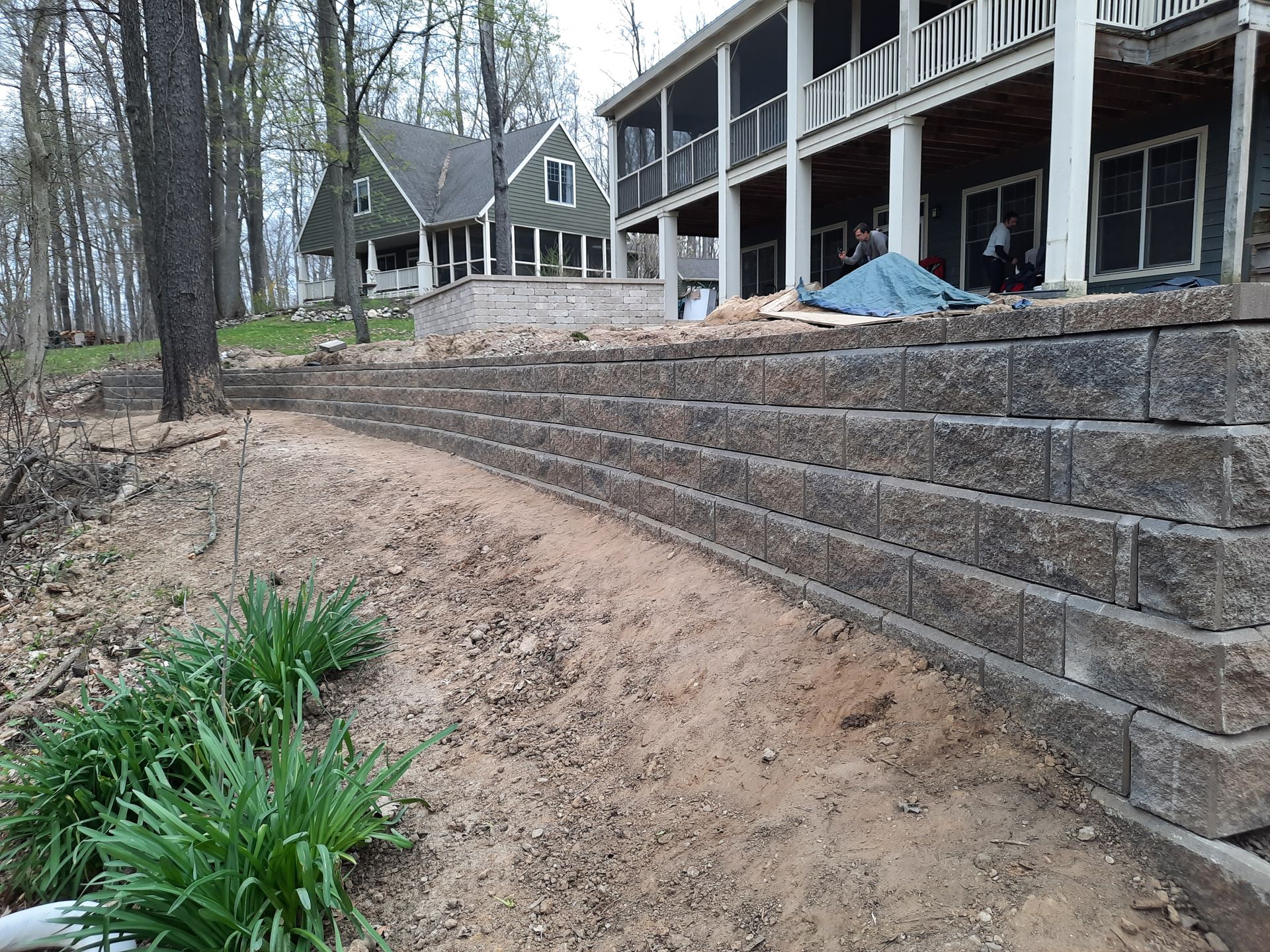 A stone wall is being built in front of a house.